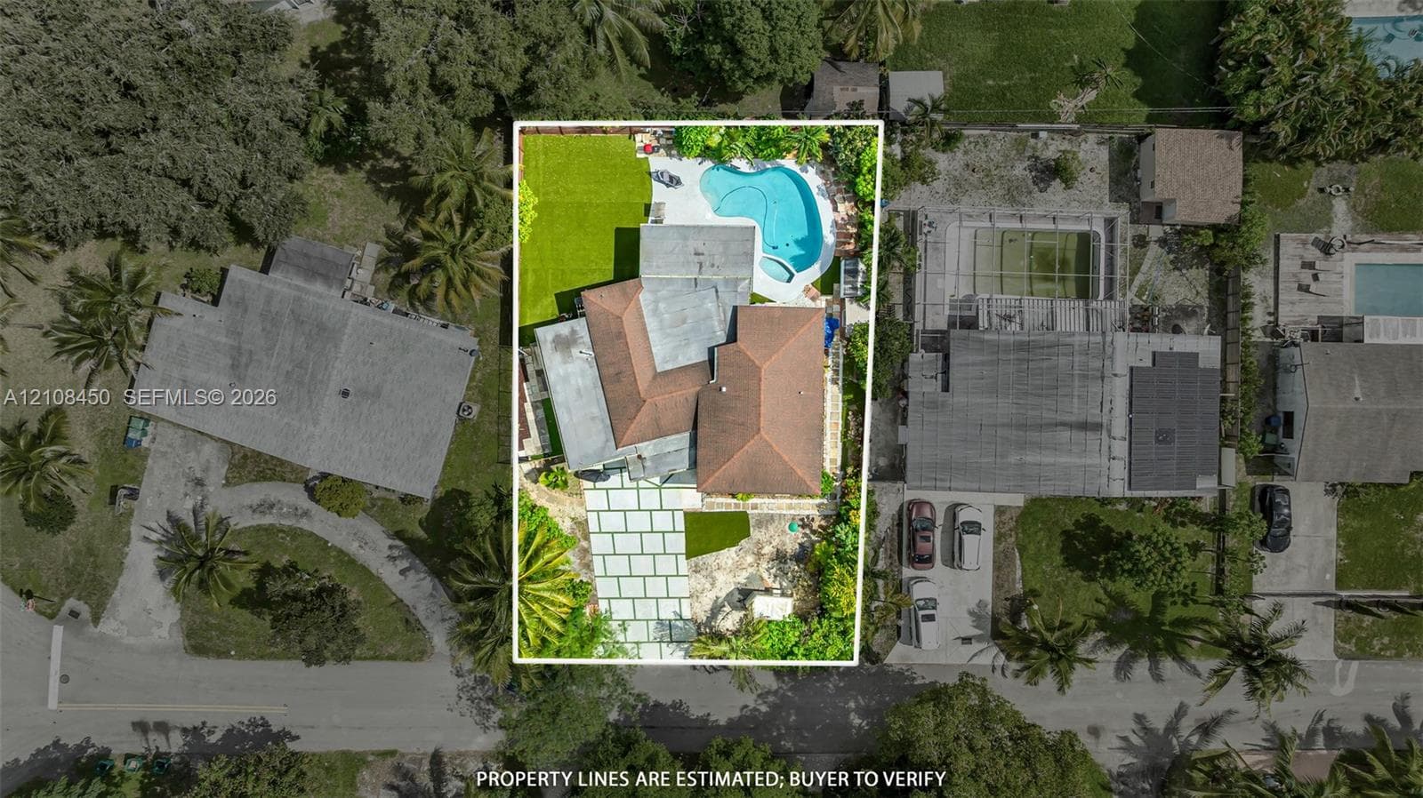 Aerial view featuring a paved driveway, hip-style roof, swimming pool, and manicured lawn