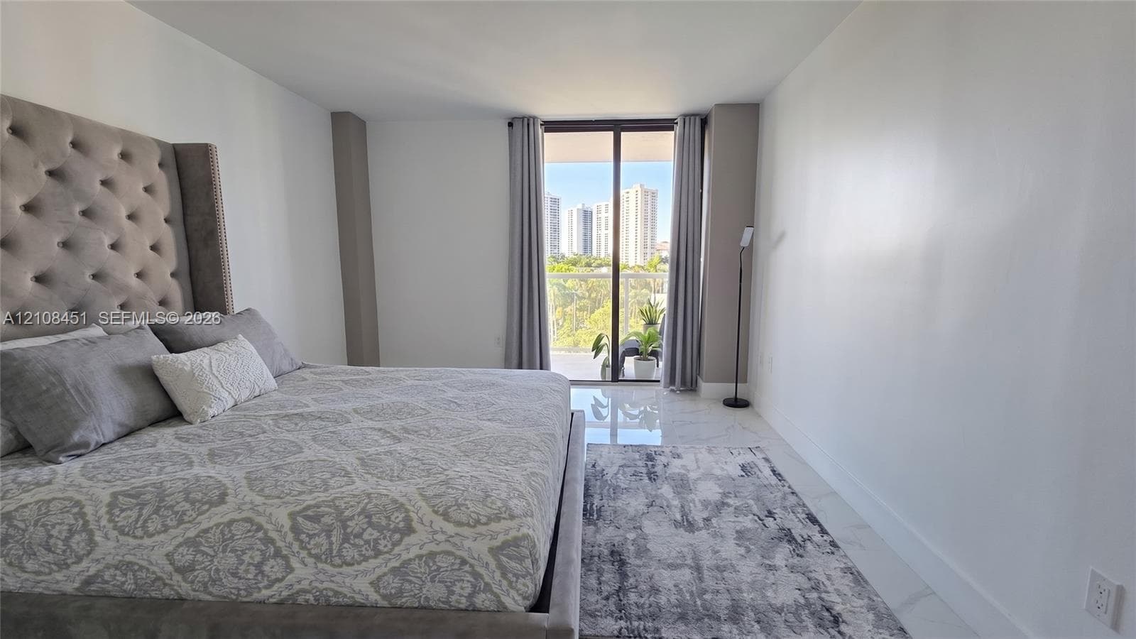 Neutral-tone interior featuring polished stone-finish flooring and a glass sliding door providing access to a private balcony