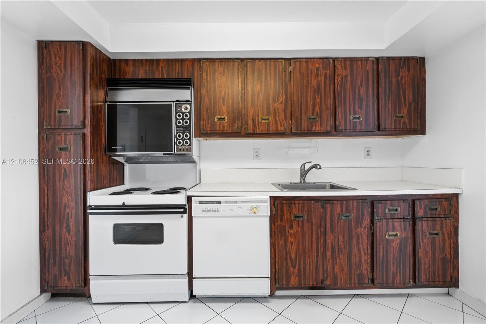Kitchen featuring wood-grain cabinetry, solid surface countertops, white electric range with built-in microwave, integrated dishwasher, and stainless steel sink