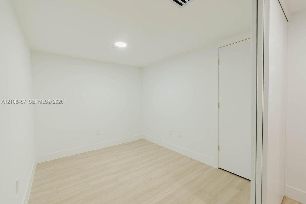 Interior space featuring light-toned wood-finish flooring, crisp white walls, recessed ceiling lighting, and a closet with sliding doors