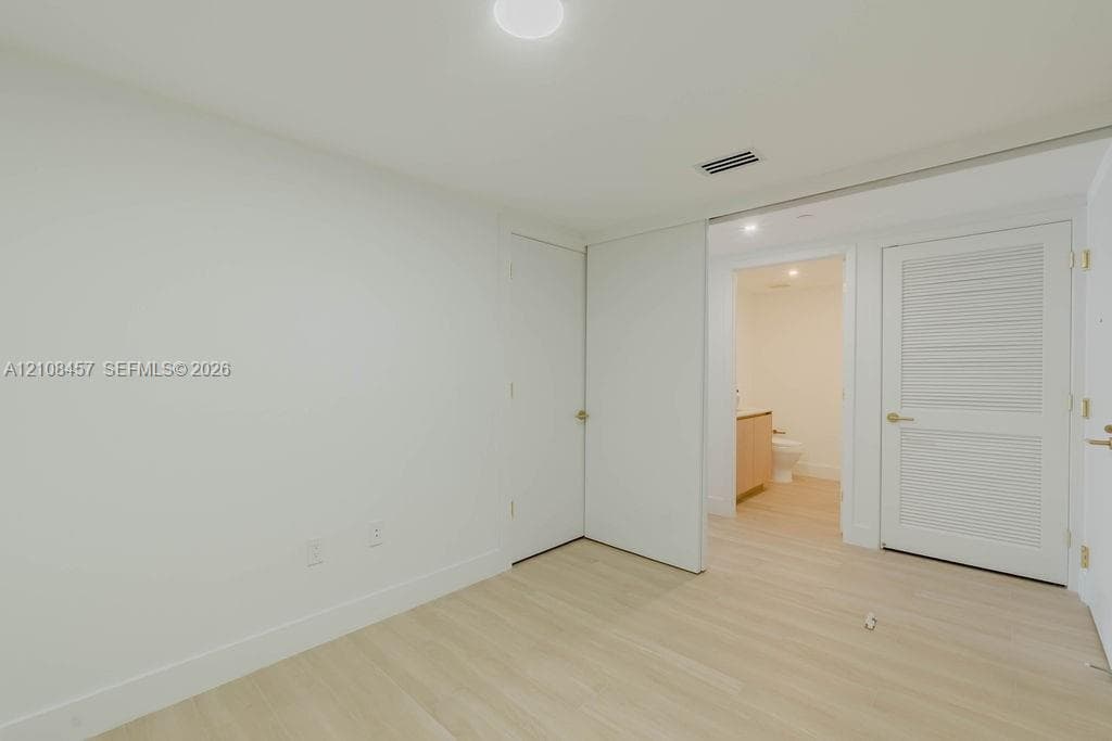 Interior space featuring wood-finish flooring, a louvered closet door, a flush-mount ceiling light fixture, and a neutral color palette