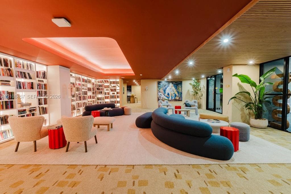 Floor-to-ceiling built-in bookcases with integrated lighting, recessed tray ceiling, wood-slat ceiling accent, and recessed lighting