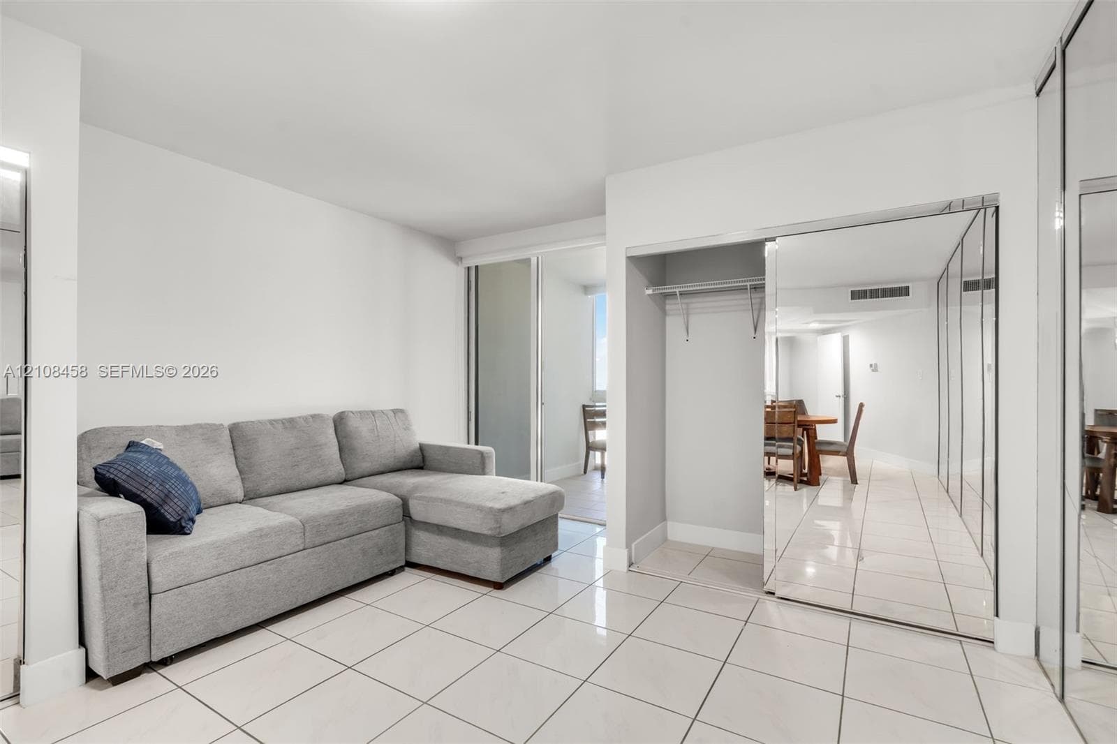 Neutral-toned tile flooring, mirrored sliding closet doors, and open-concept architectural design