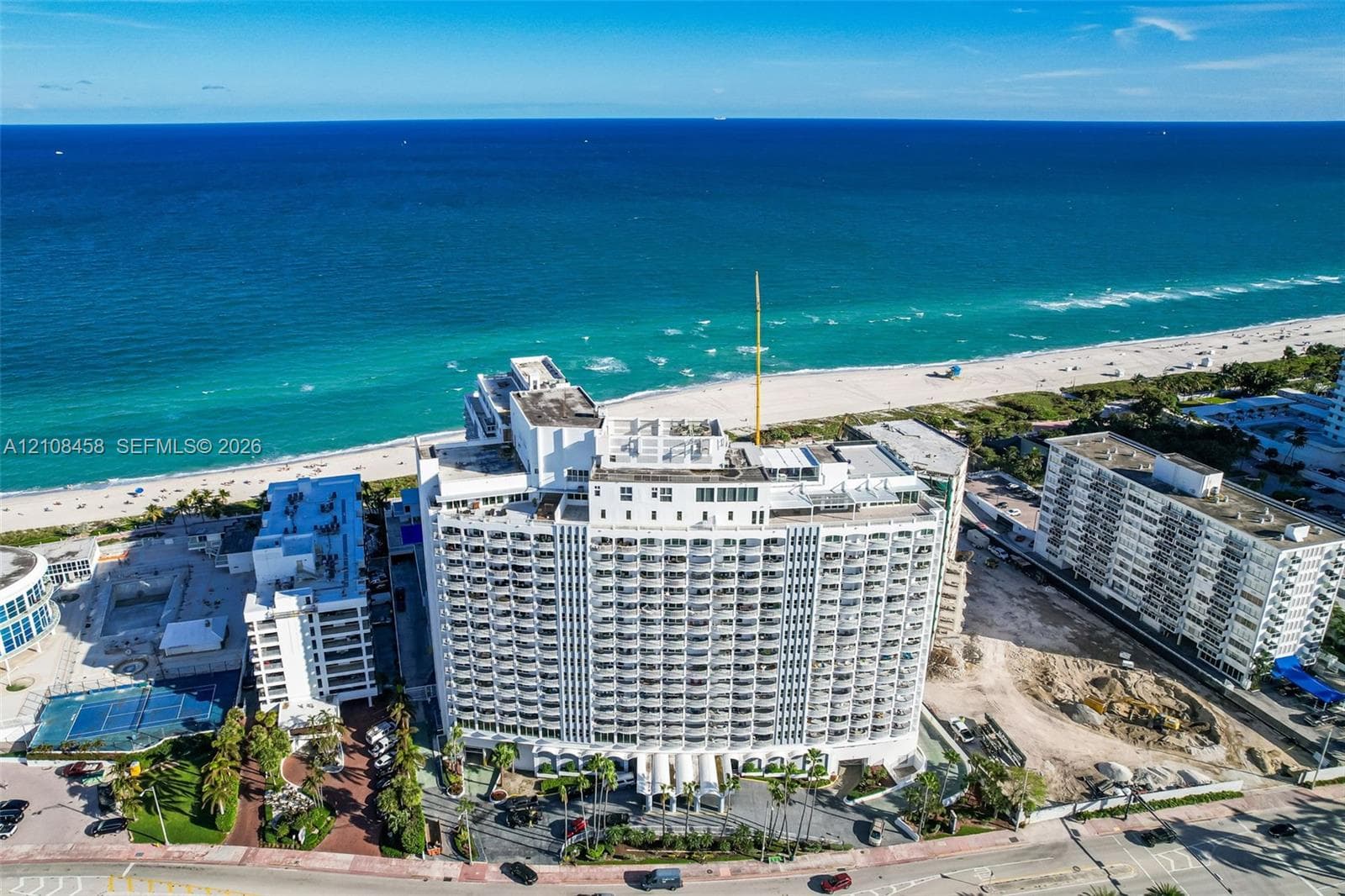High-rise multi-story building featuring tiered balconies, a rooftop deck, and direct proximity to the oceanfront