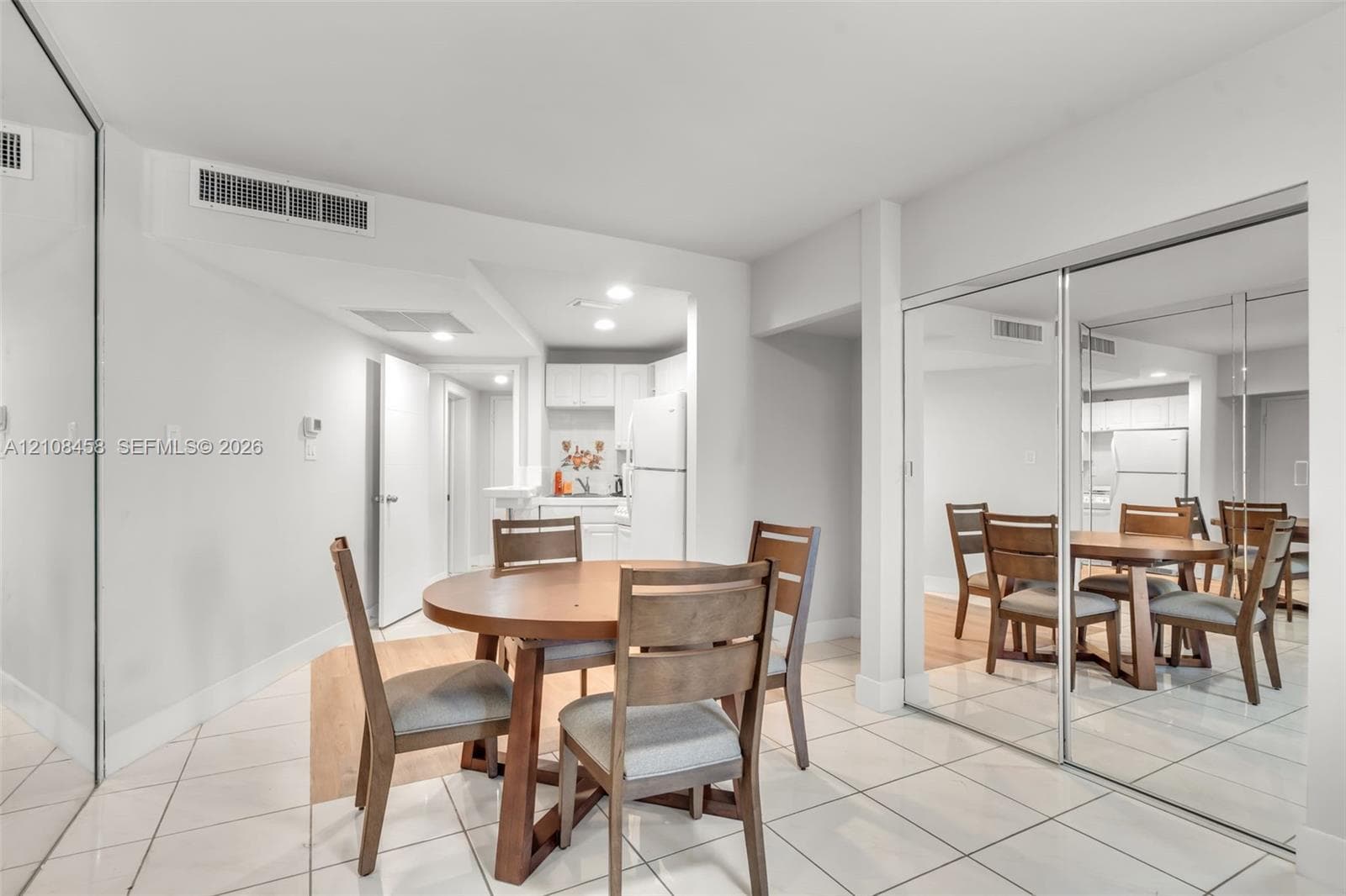Bright interior space featuring polished tile flooring, wall-to-wall mirrored closet doors, and recessed lighting