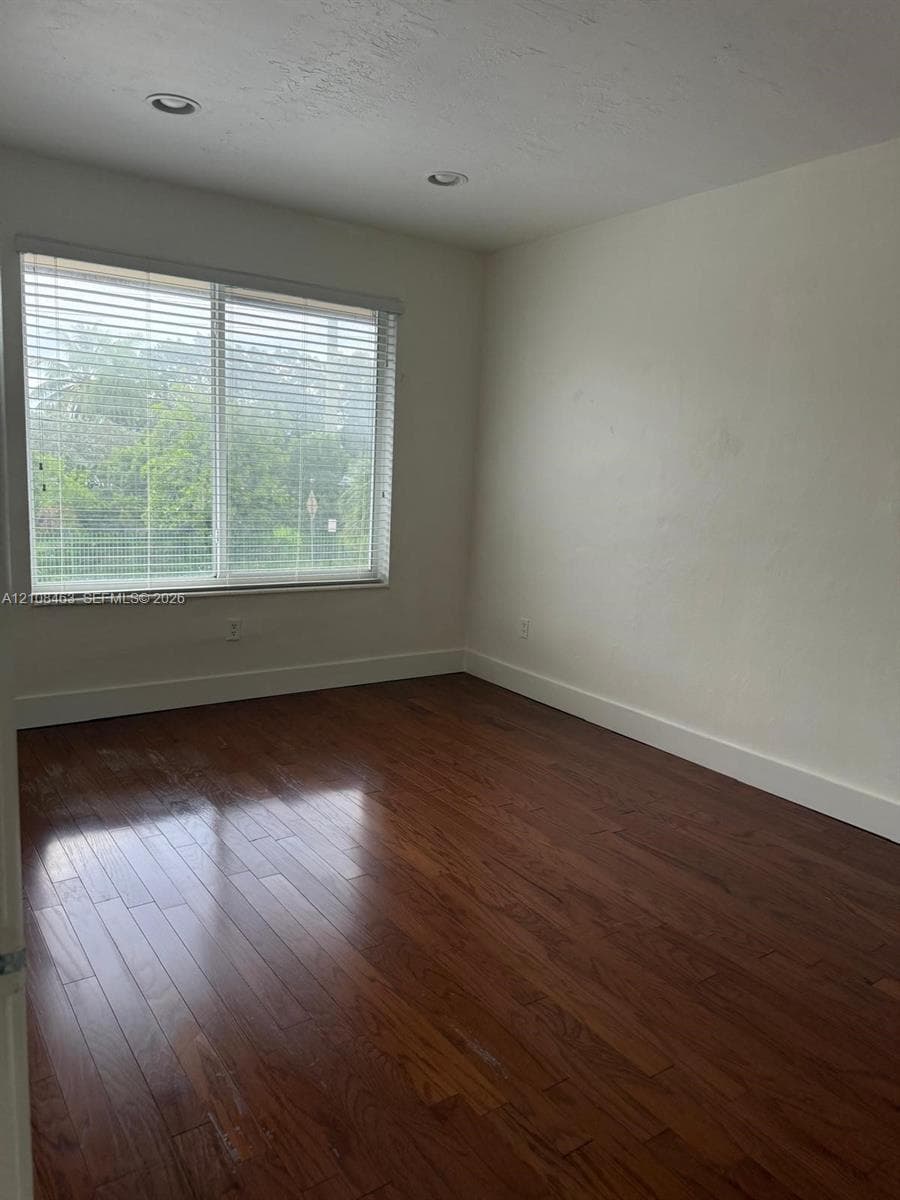 Room featuring wood-finish flooring, recessed lighting, and a large window with horizontal blinds