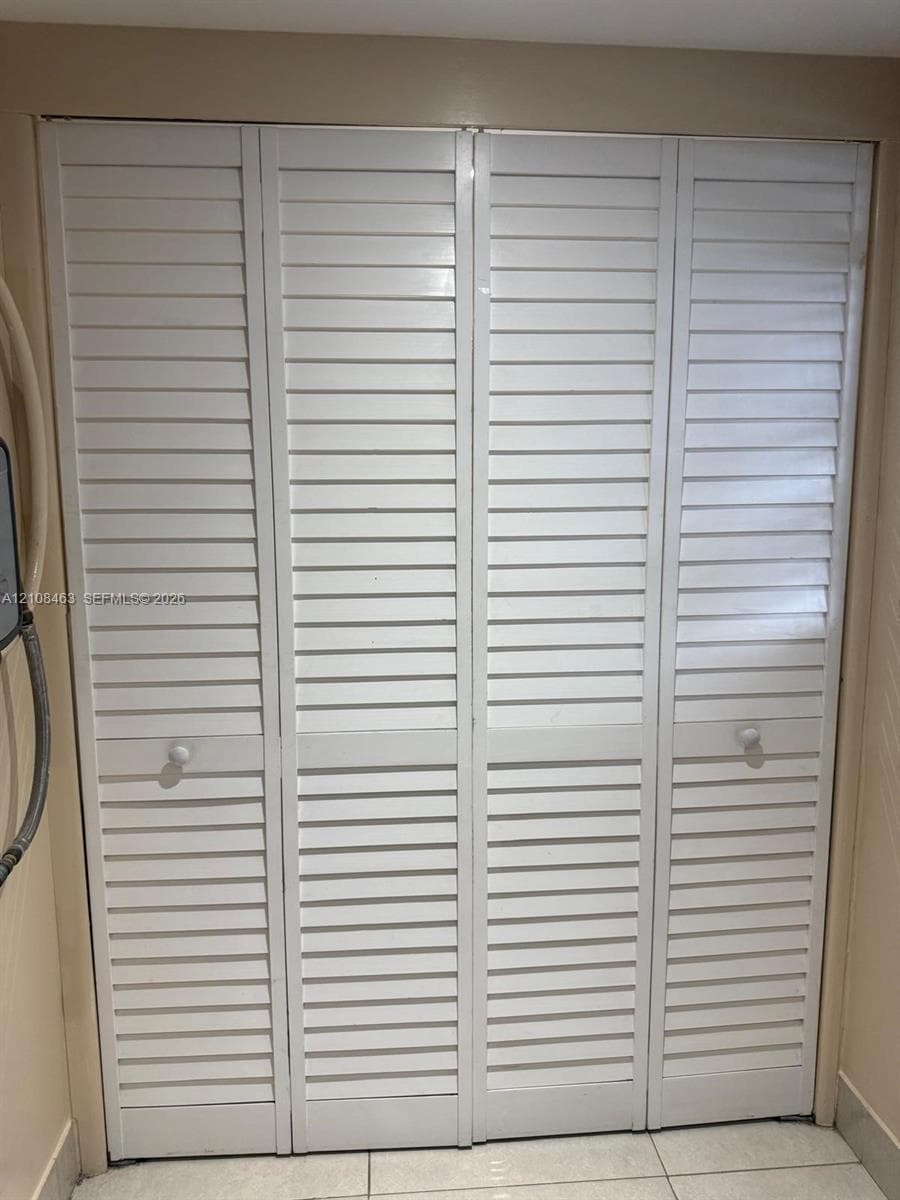Bi-fold closet doors featuring white louvered panels and round hardware pulls