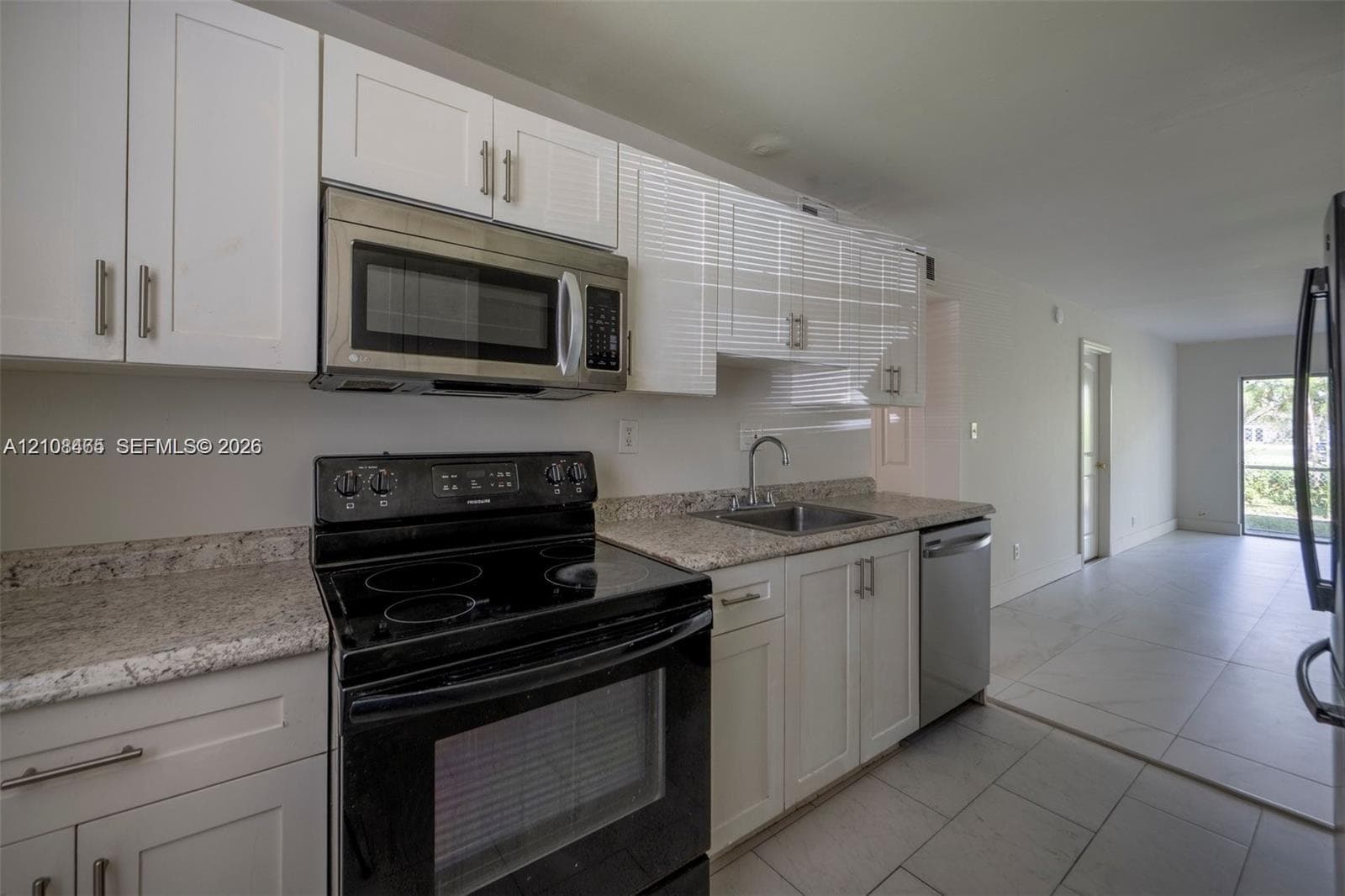 Kitchen featuring white shaker-style cabinetry, stone countertops, stainless steel microwave, black electric range, and tile flooring