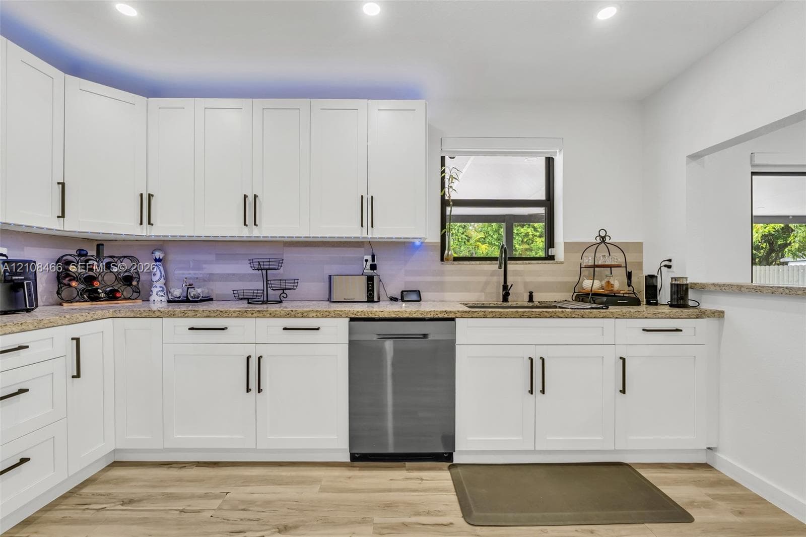 Kitchen featuring white shaker-style cabinetry, stone-finish countertops, stainless steel dishwasher, wood-finish flooring, and recessed ceiling lighting