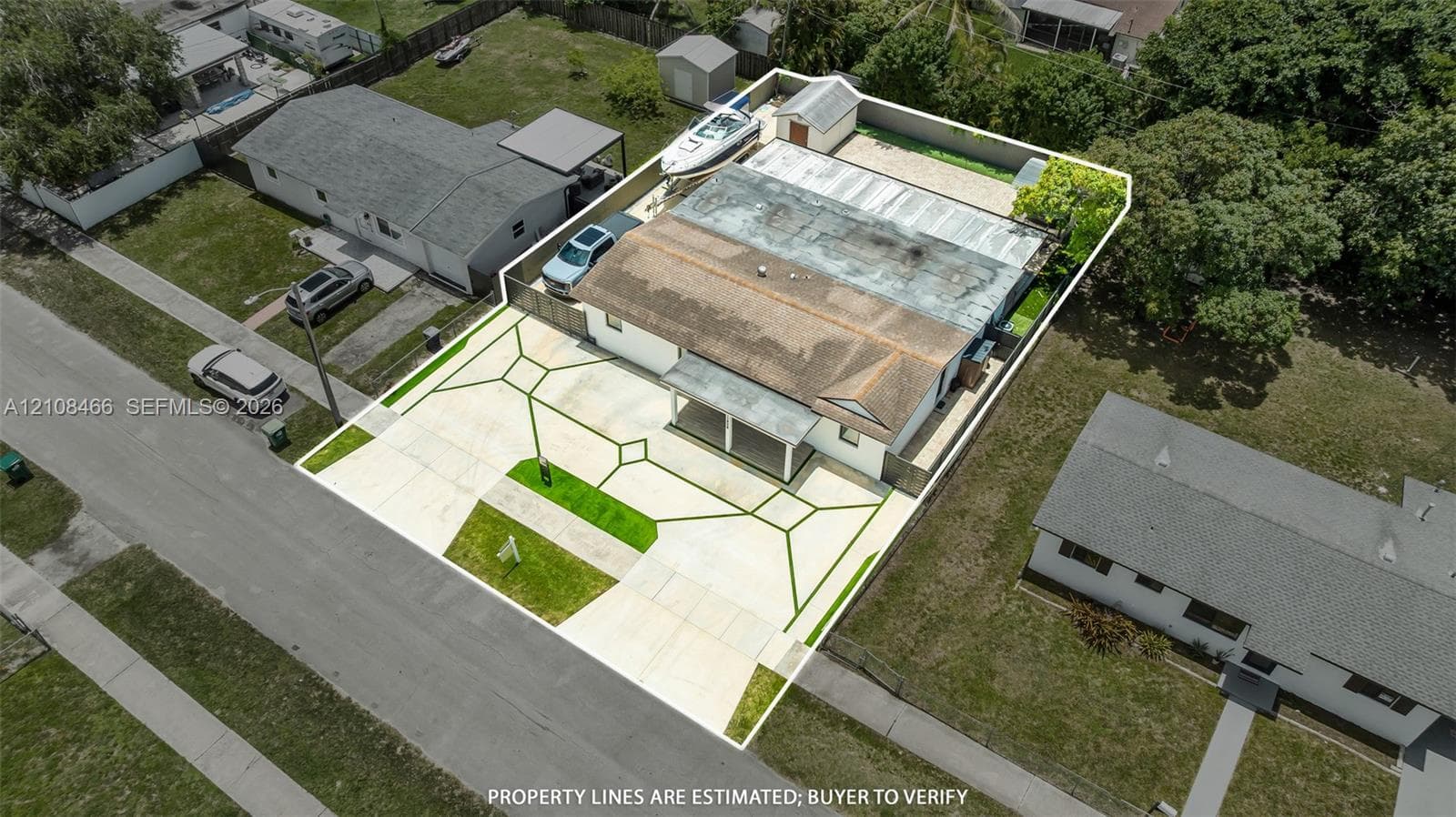 Aerial perspective of property featuring a wide concrete driveway, covered front entryway, fenced perimeter, and detached storage structure
