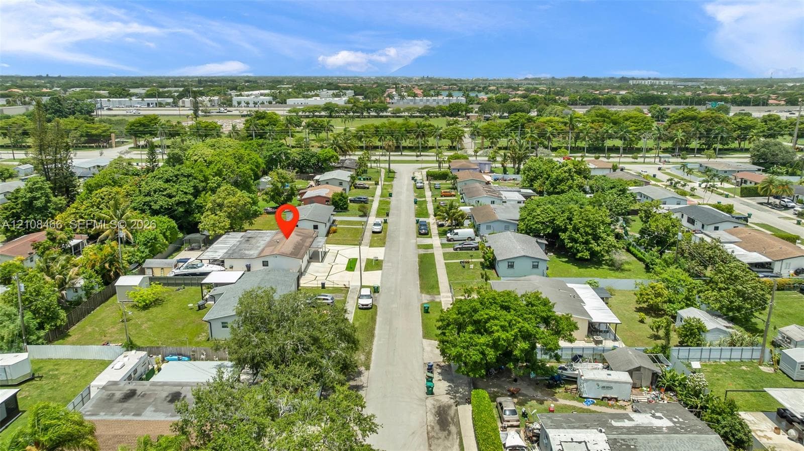 Aerial perspective of a residential property featuring a paved driveway, a spacious backyard, and mature surrounding landscaping