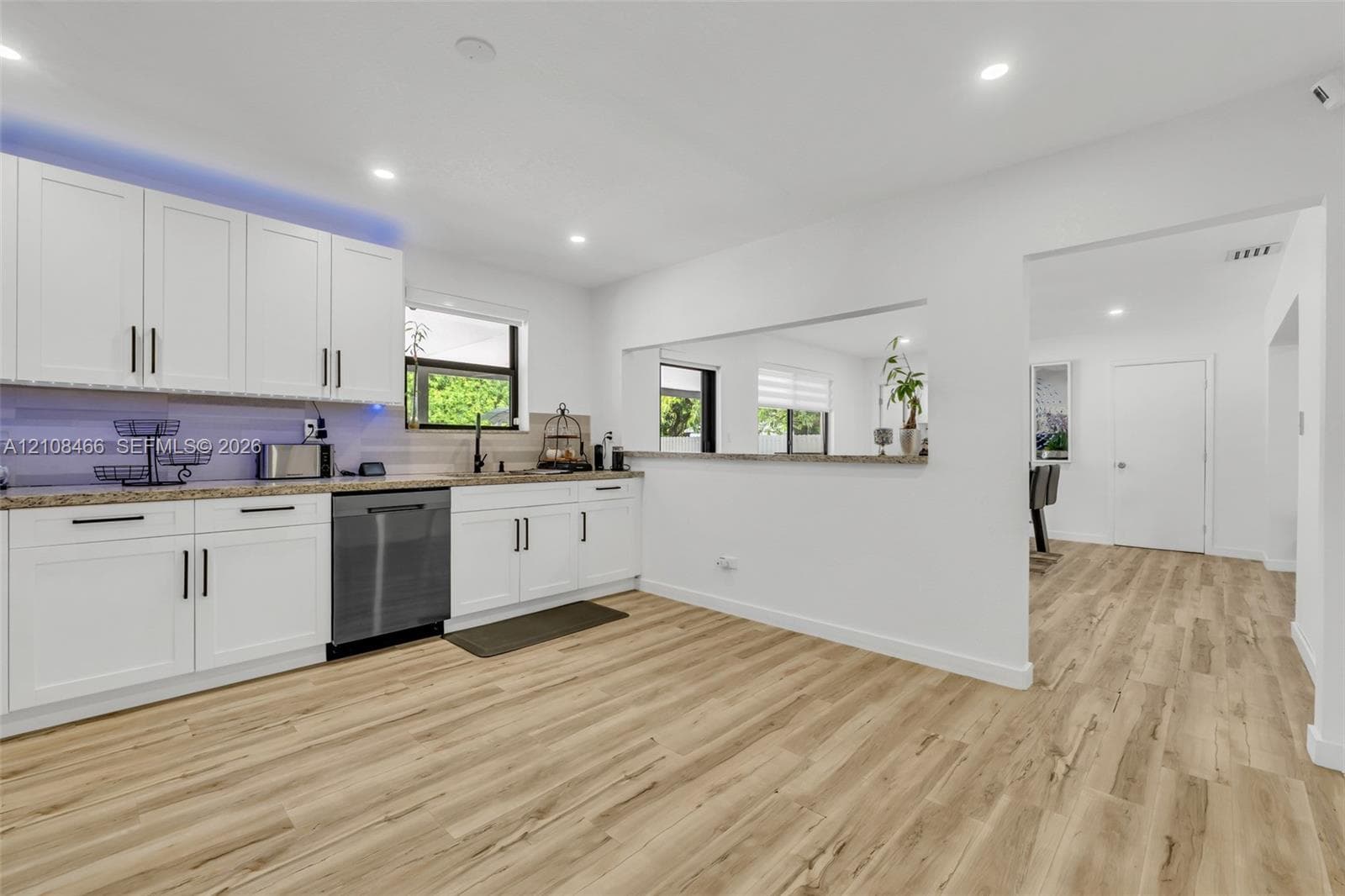 Kitchen featuring white shaker-style cabinetry, stone-finish countertops, wood-finish flooring, recessed lighting, and a stainless steel dishwasher