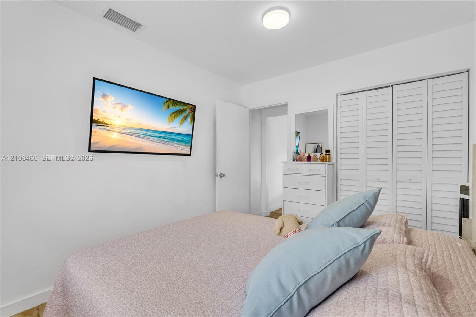 Interior room featuring white walls, dual louvered-panel closet doors, and a ceiling-mounted light fixture
