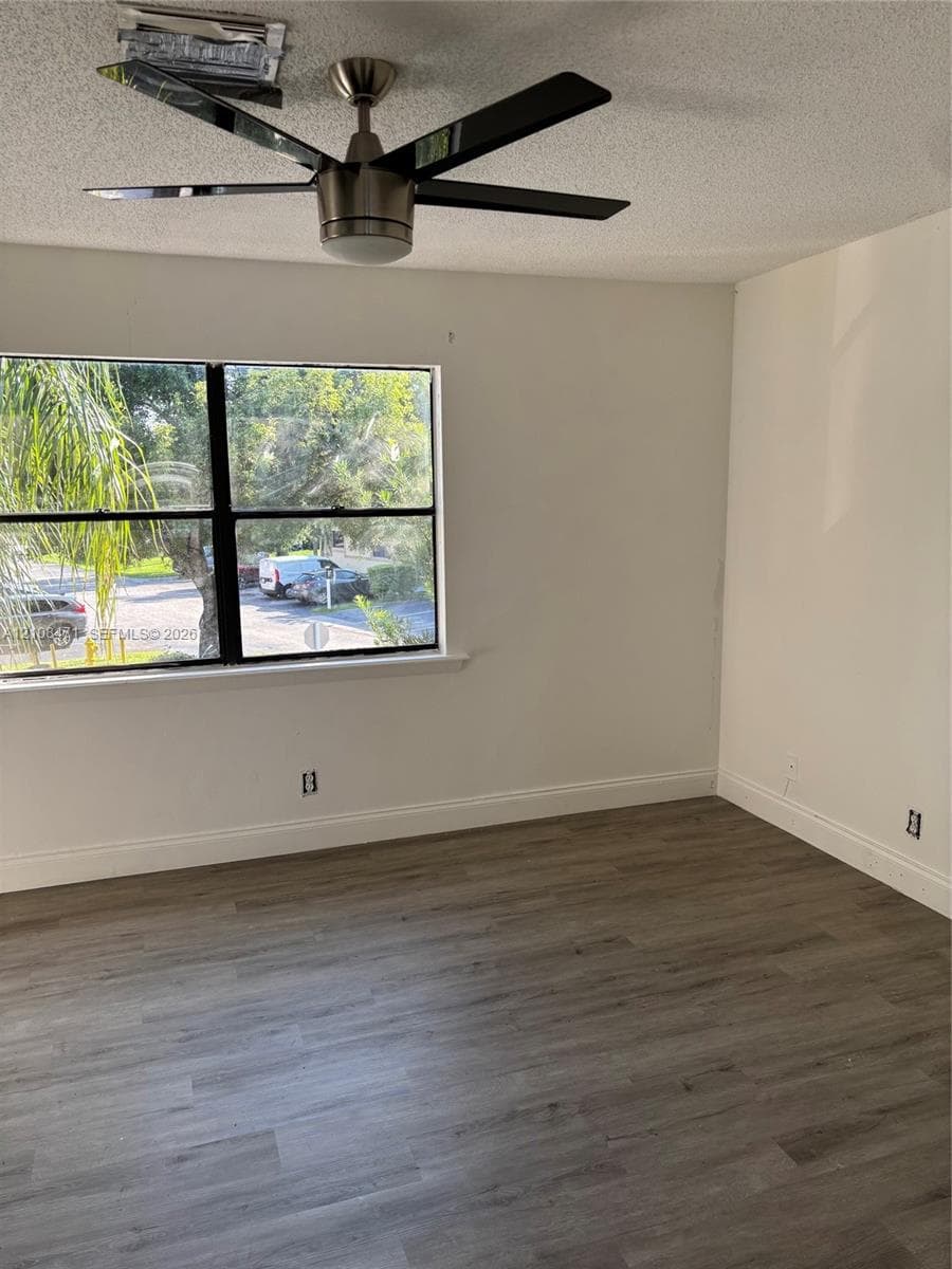 Wood-finish flooring, multi-pane window with black framing, and modern ceiling fan with integrated light fixture