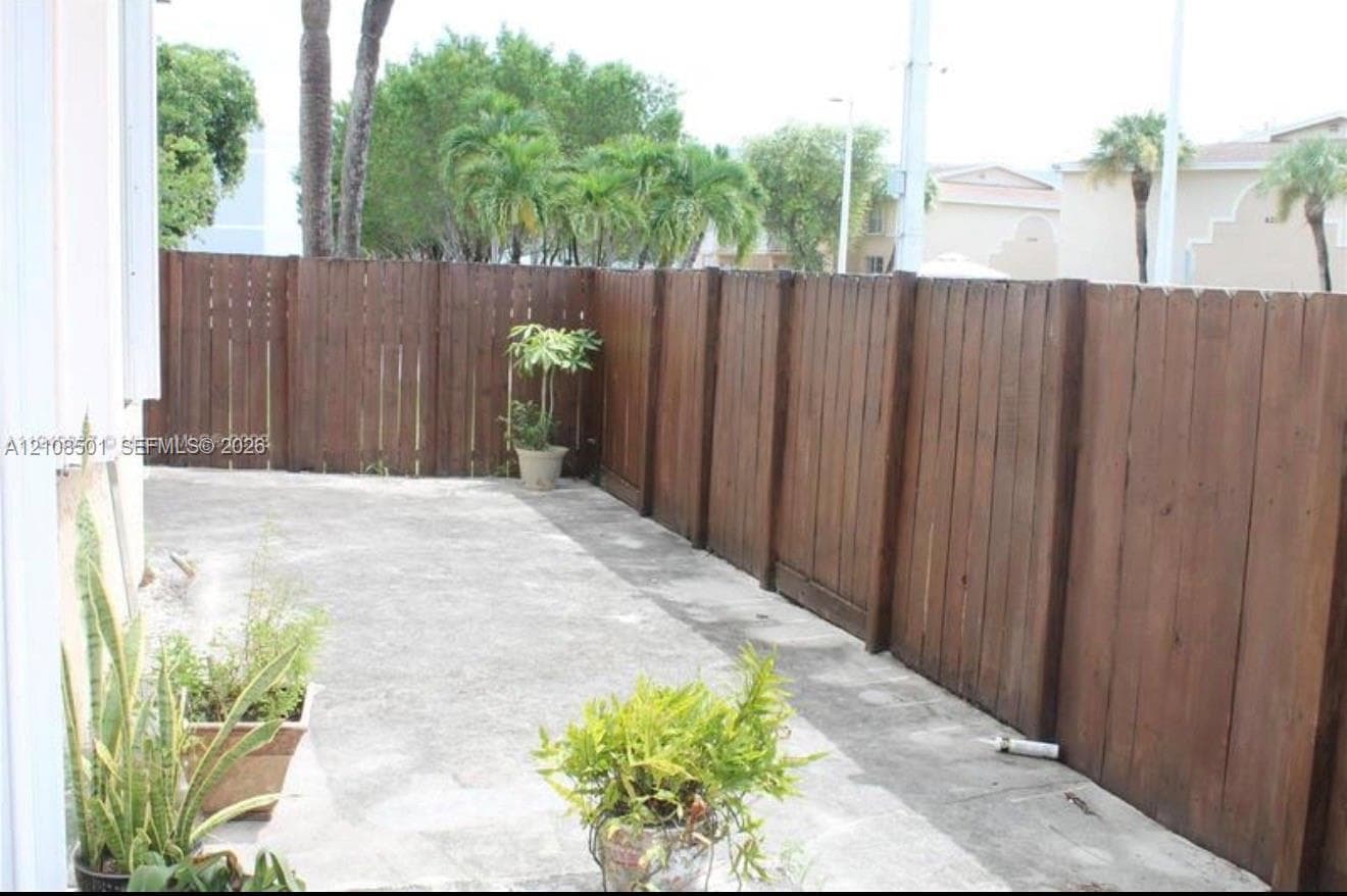 Enclosed patio featuring a concrete surface and a full-height wood-finish perimeter fence