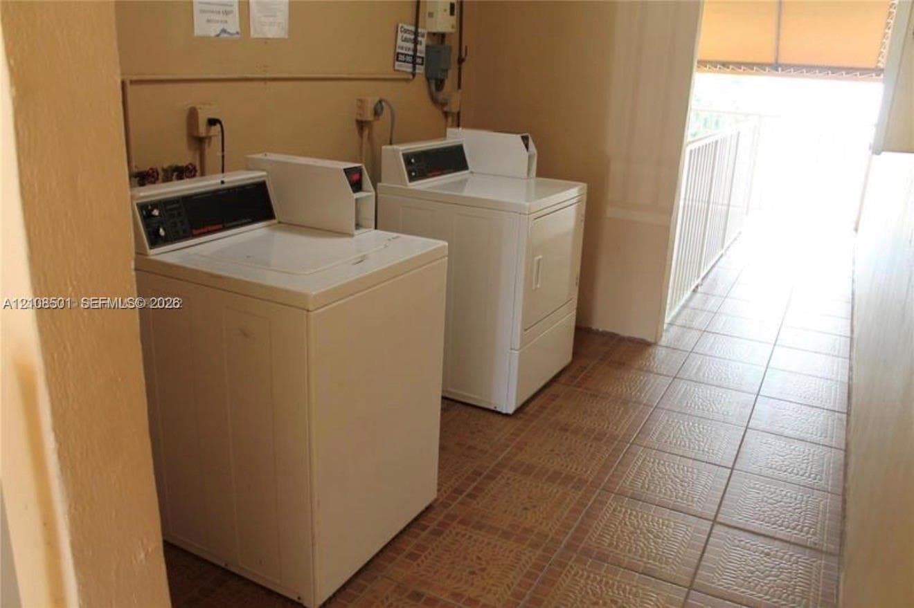 Laundry area featuring ceramic tile flooring, a dedicated washer and dryer, and an exterior metal railing