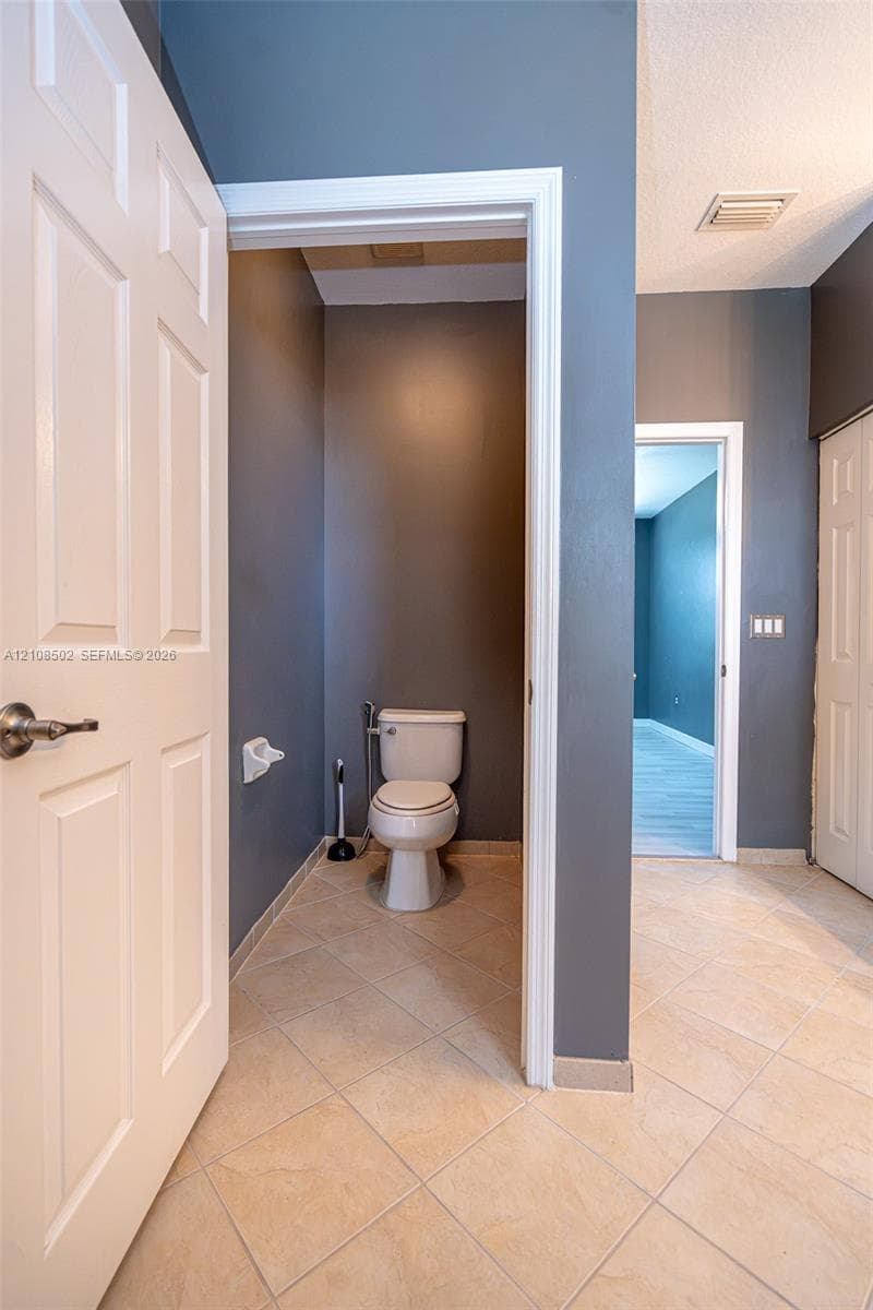 Ceramic tile flooring, white six-panel interior doors, and solid-surface walls