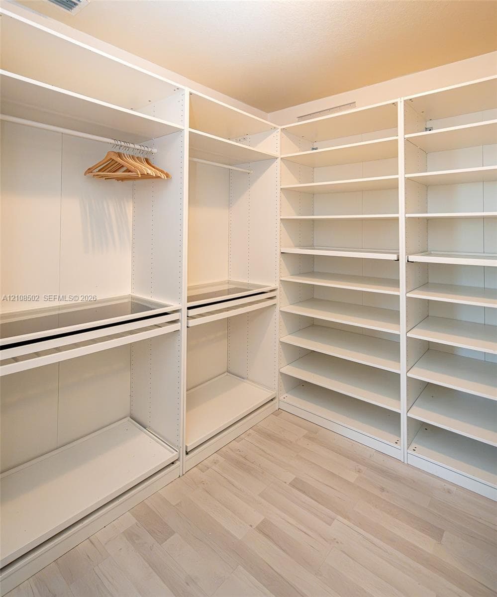 Custom built-in closet organization system featuring adjustable shelving, integrated hanging rods, and wood-finish flooring