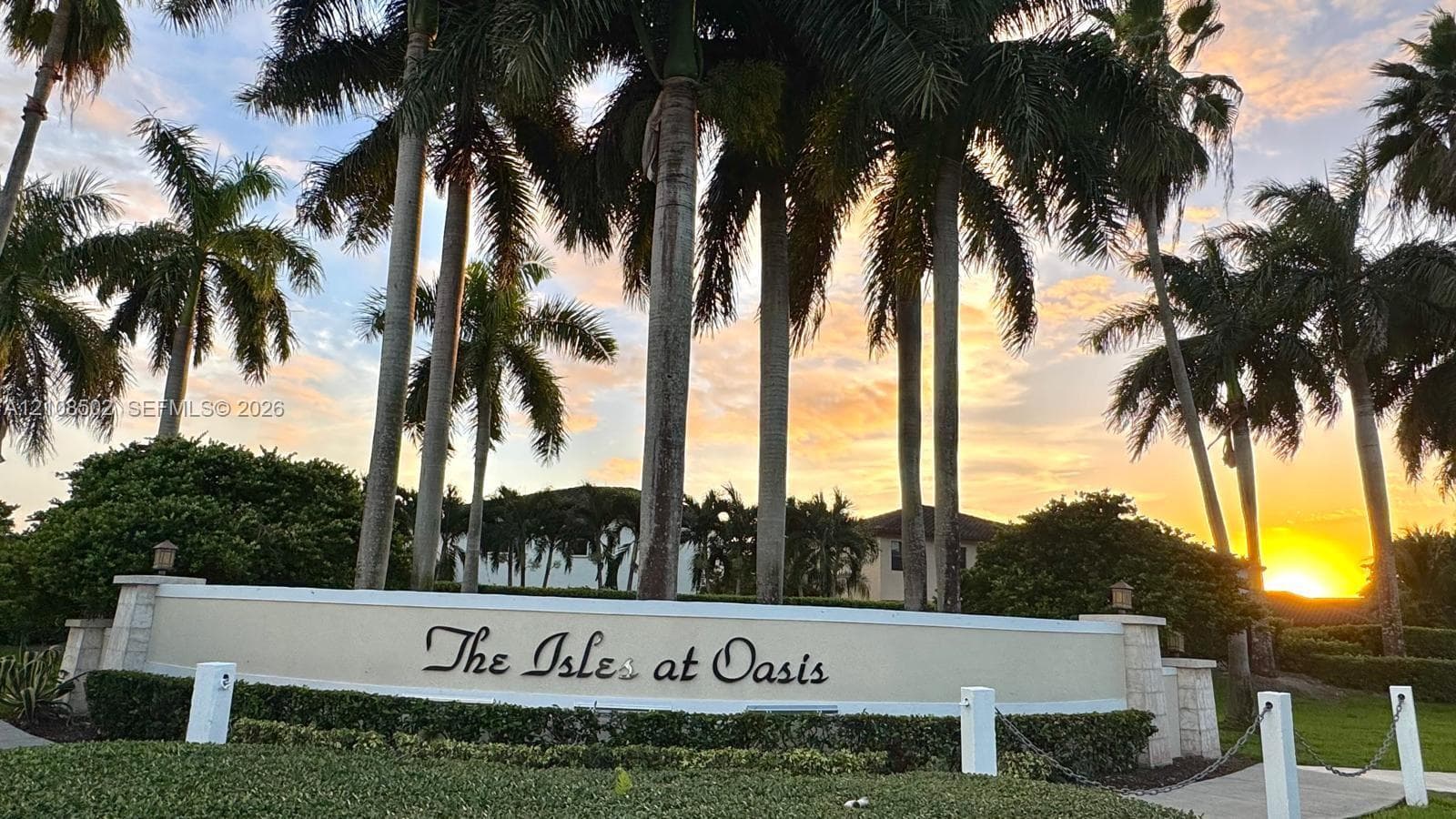 Stone masonry signage featuring a cast-stone finish, complemented by mature palm trees and landscaped greenery
