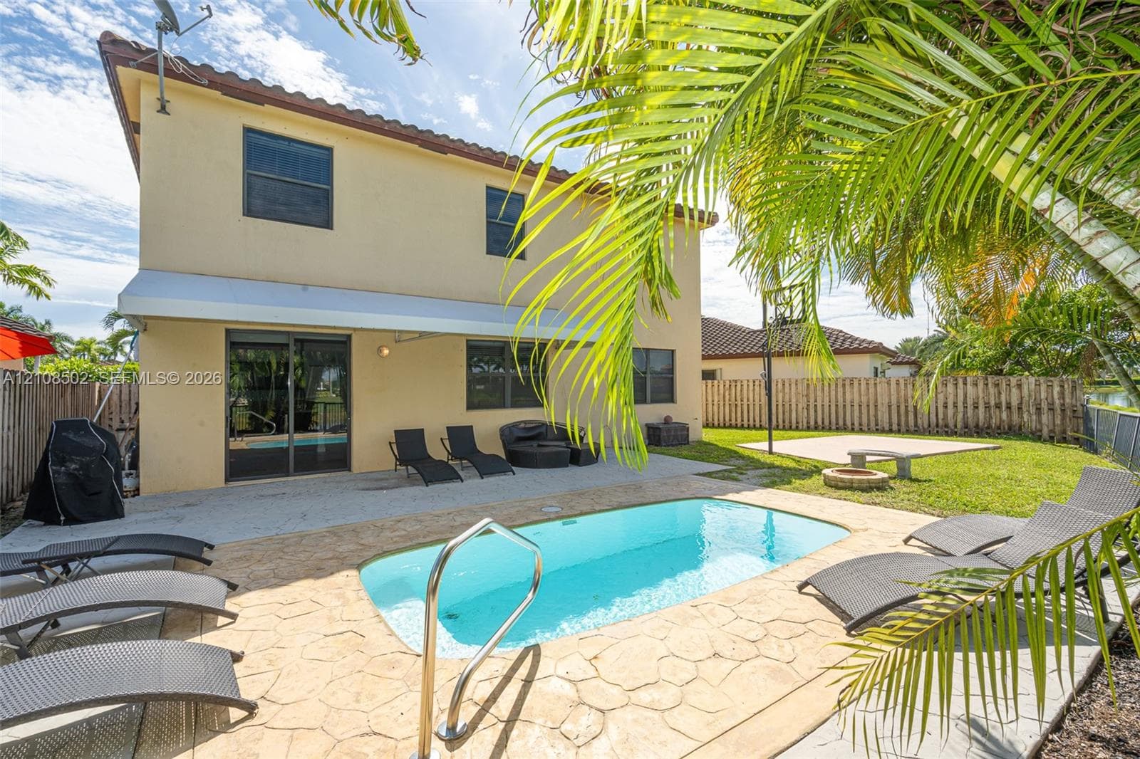 Rear exterior featuring a stucco facade, concrete tile roofing, a paved patio, an in-ground swimming pool, and a fenced backyard