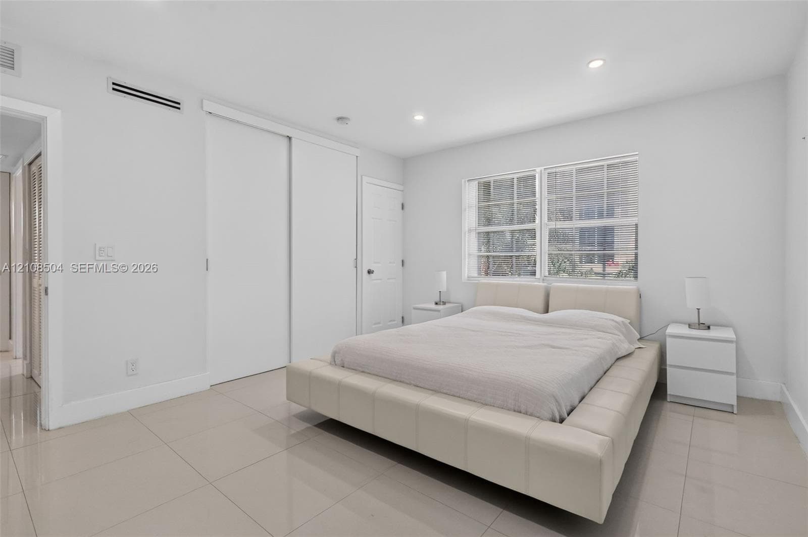 Neutral-toned tile flooring, recessed ceiling lighting, multi-pane windows, and dual sliding closet doors
