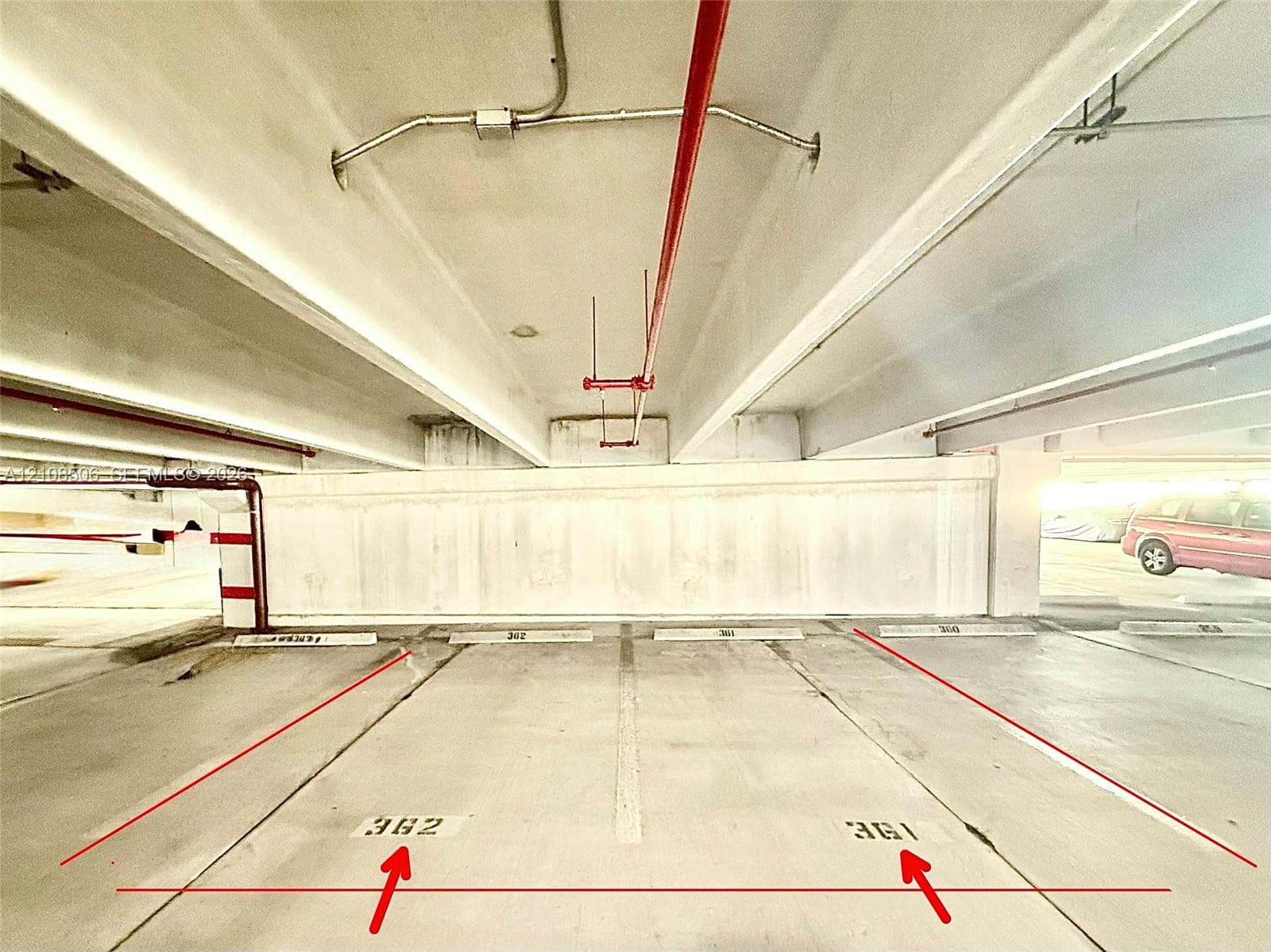 Covered parking structure featuring concrete flooring, marked stall numbers 361 and 362, and overhead fire suppression infrastructure