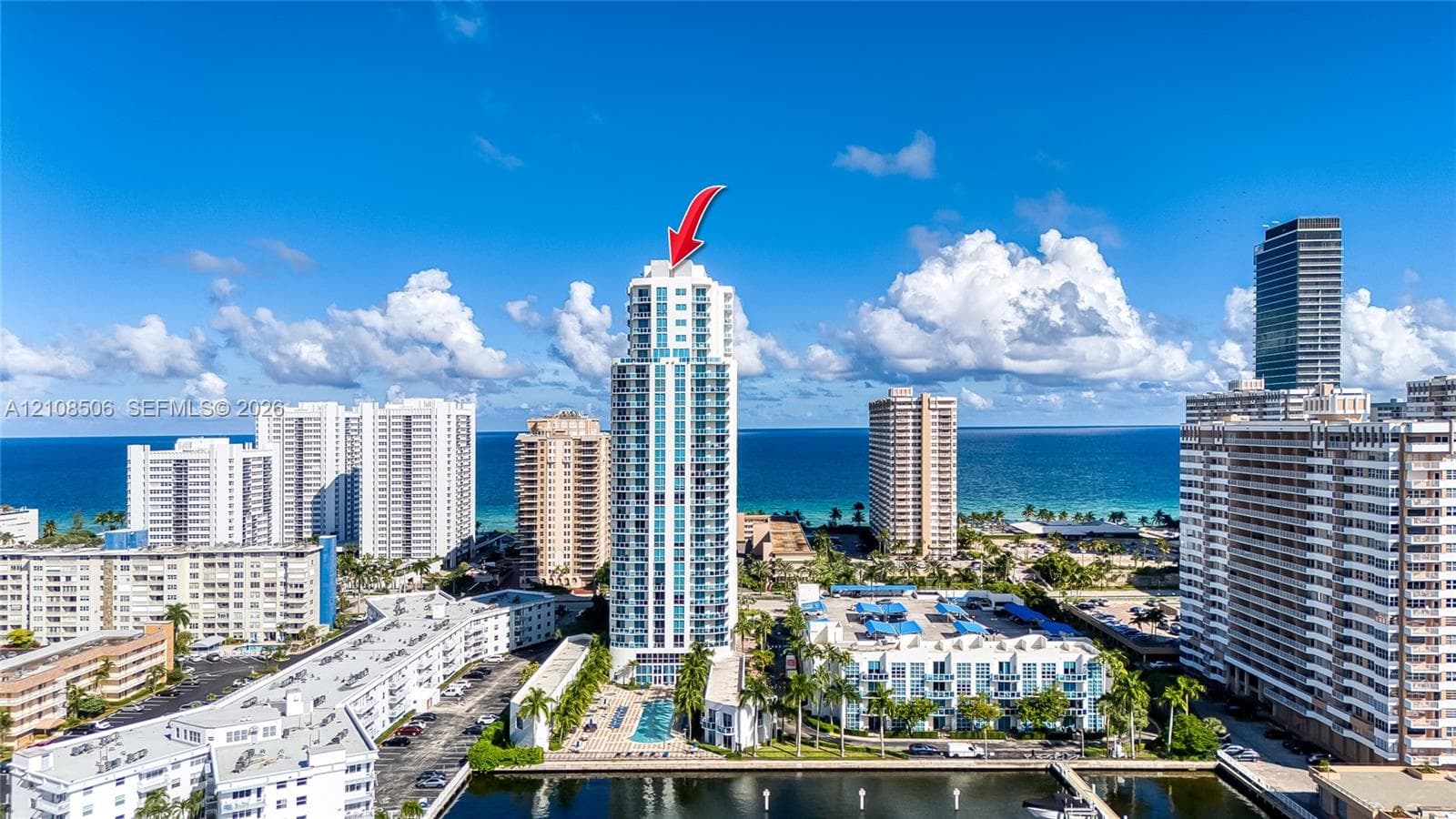 High-rise condominium tower featuring private balconies, integrated glass exterior detailing, and a ground-level swimming pool