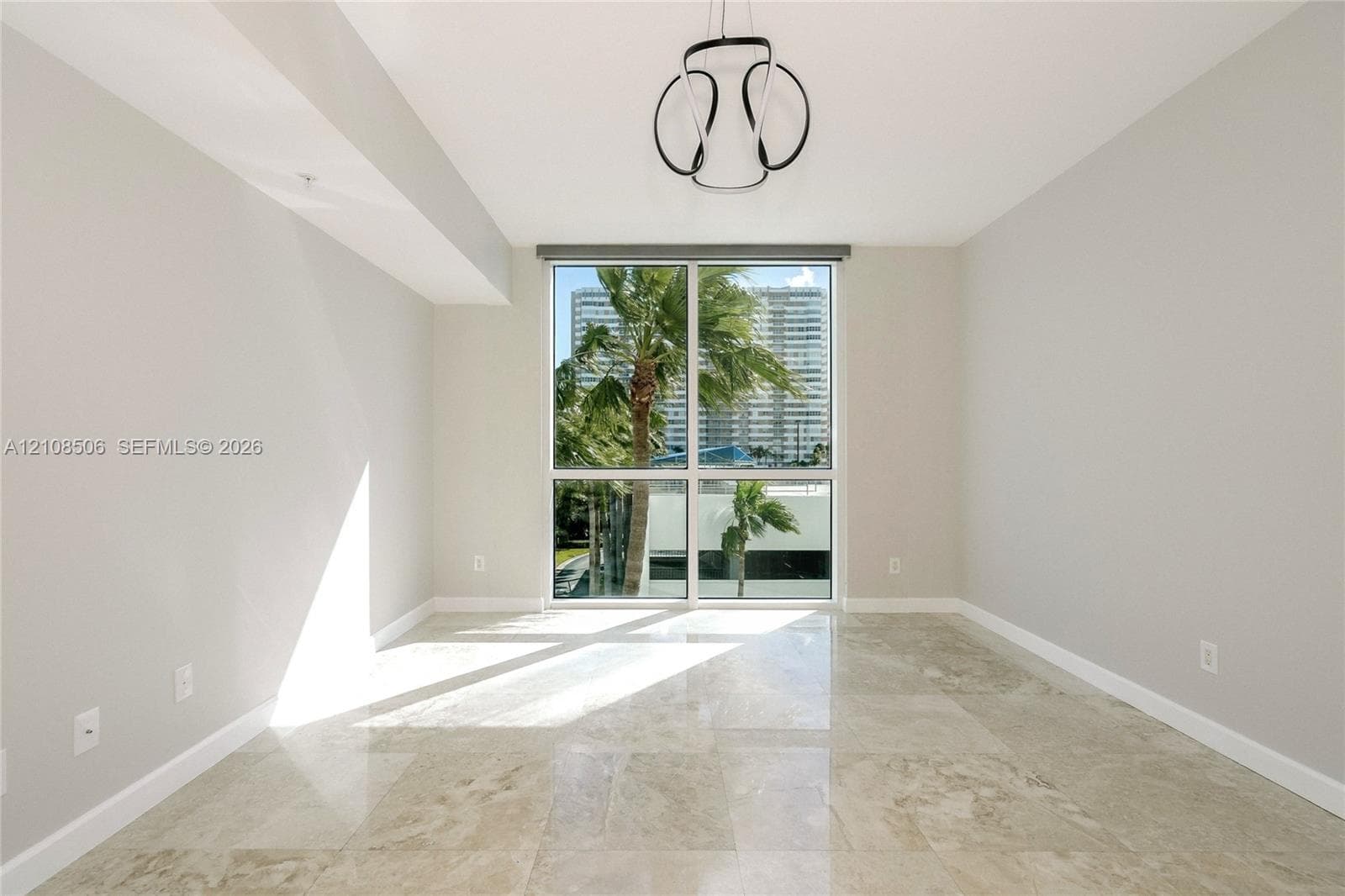 Neutral-toned space featuring polished stone flooring, floor-to-ceiling windows, and a modern geometric pendant light fixture