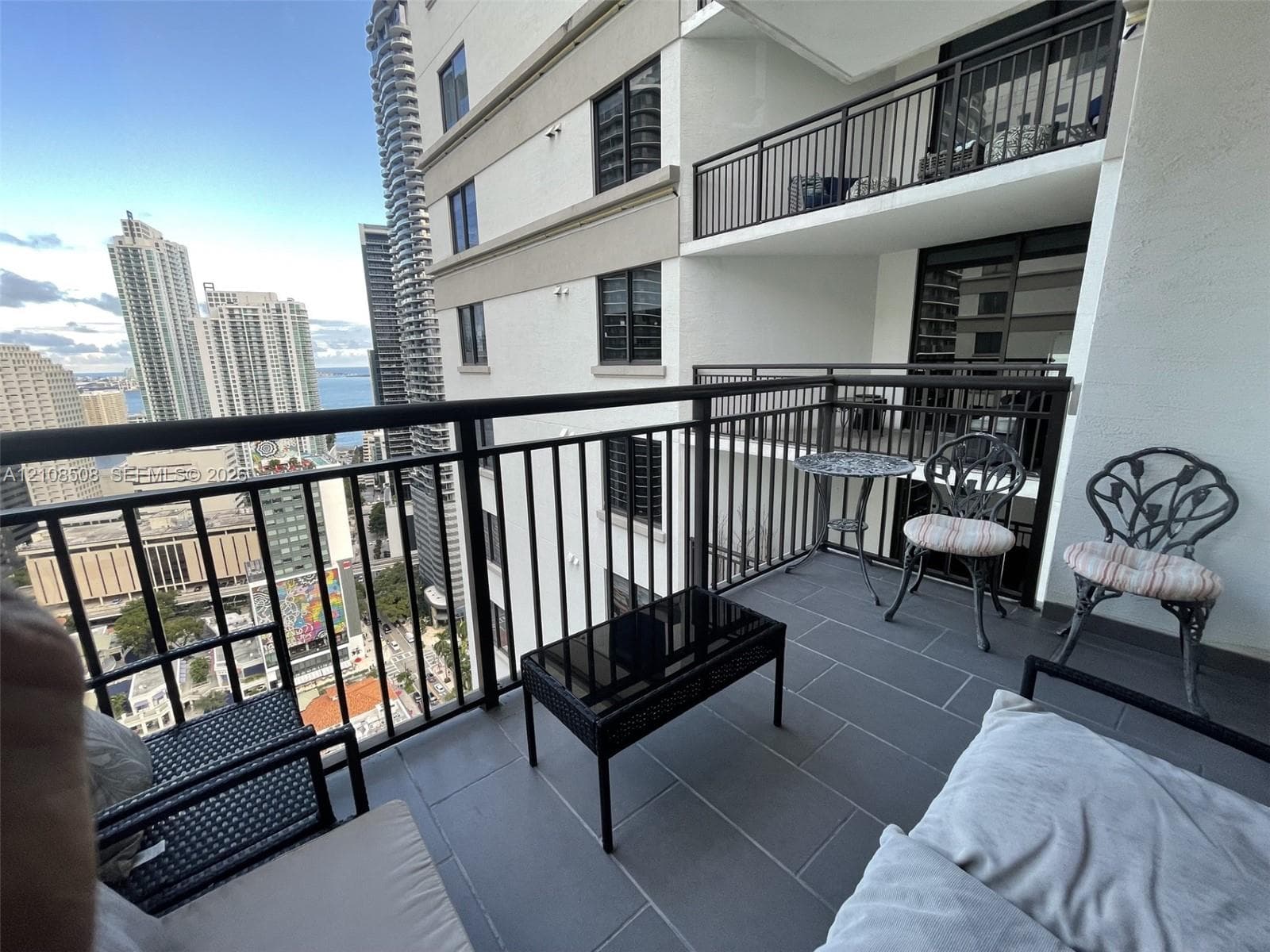Private balcony featuring dark metal railings, large-format tile flooring, and urban skyscraper surroundings