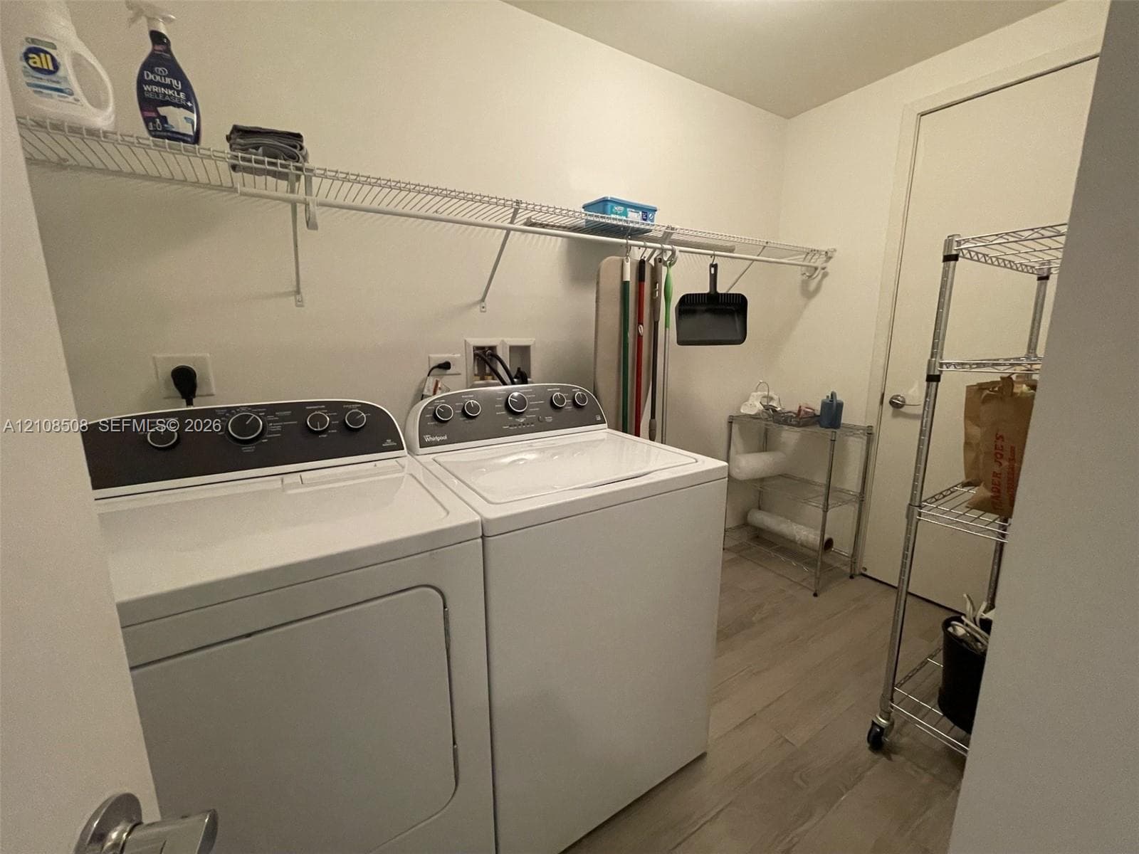 Dedicated laundry area featuring wood-finish flooring and integrated wall-mounted wire shelving