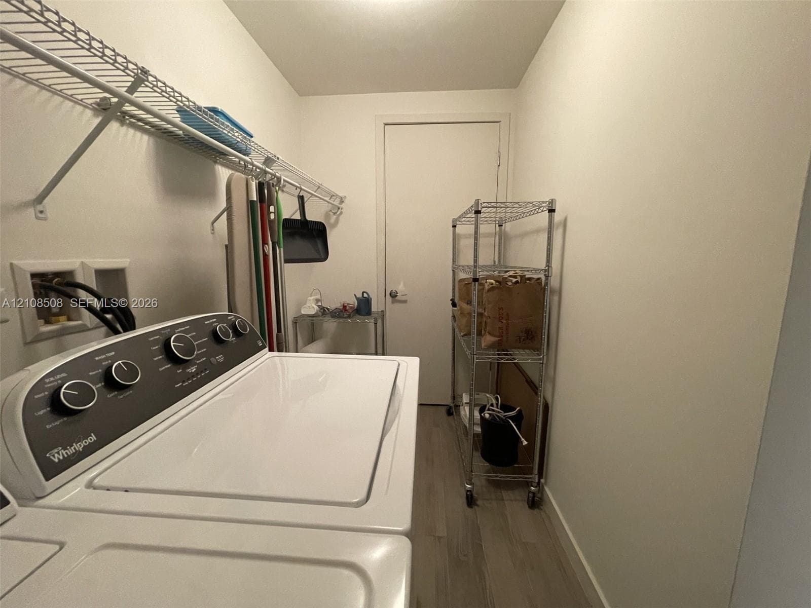 Laundry area featuring wood-finish flooring and integrated wall-mounted wire shelving