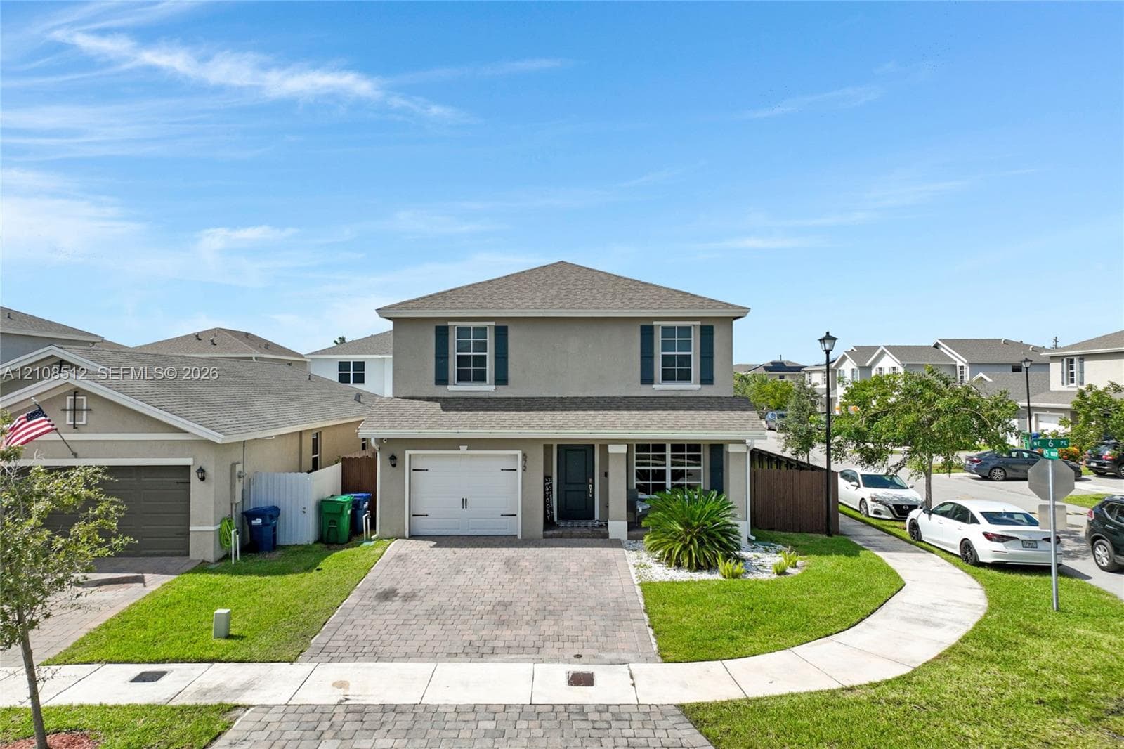 Two-story exterior featuring a stucco facade, paver driveway, single-car garage, and shuttered windows