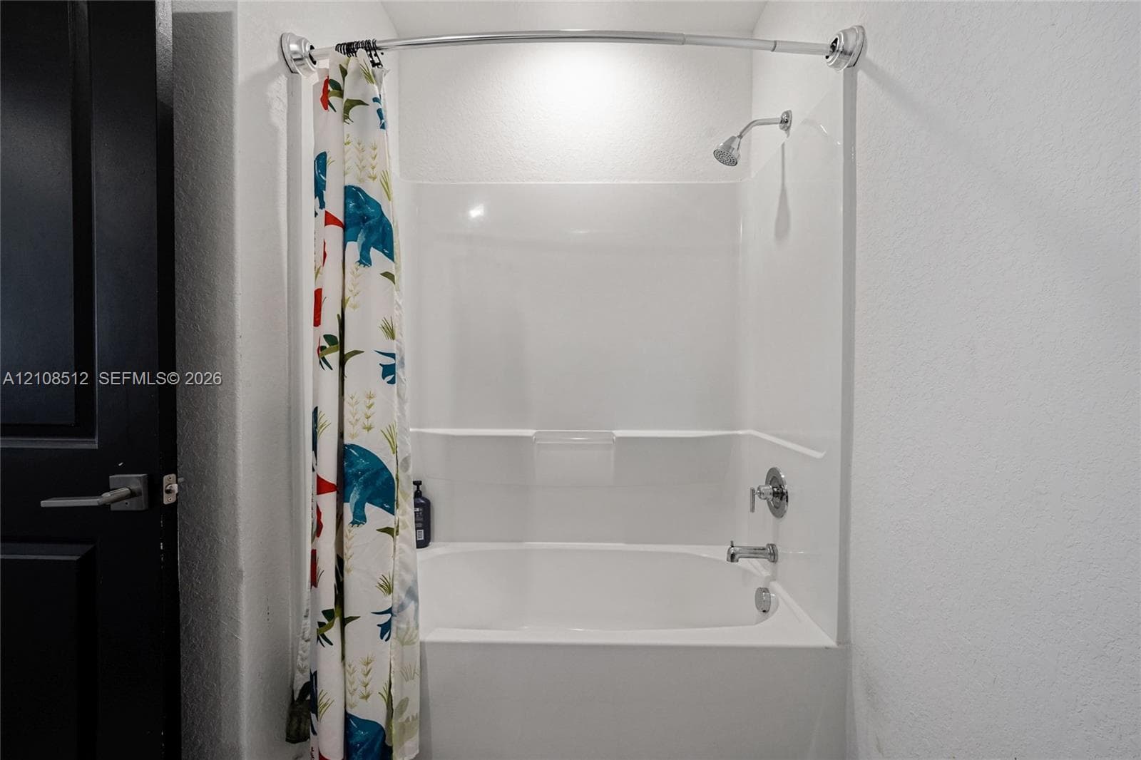 Bathtub and shower combination with a white acrylic surround, integrated shelving, a polished chrome faucet, and a wall-mounted shower head