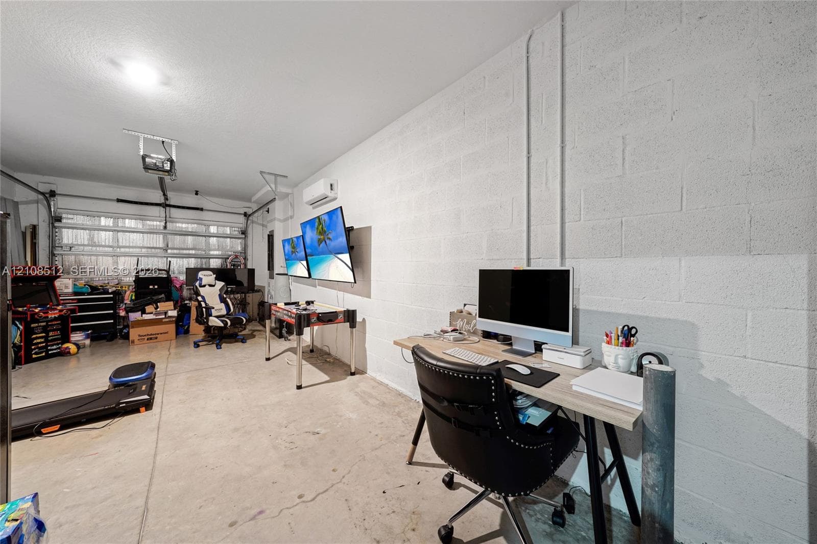 Finished garage featuring painted concrete block walls, a wall-mounted ductless mini-split system, and a motorized garage door opener