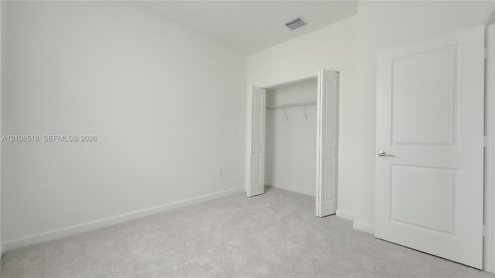 Neutral-toned carpeting, two-panel interior door, and walk-in closet with built-in shelving