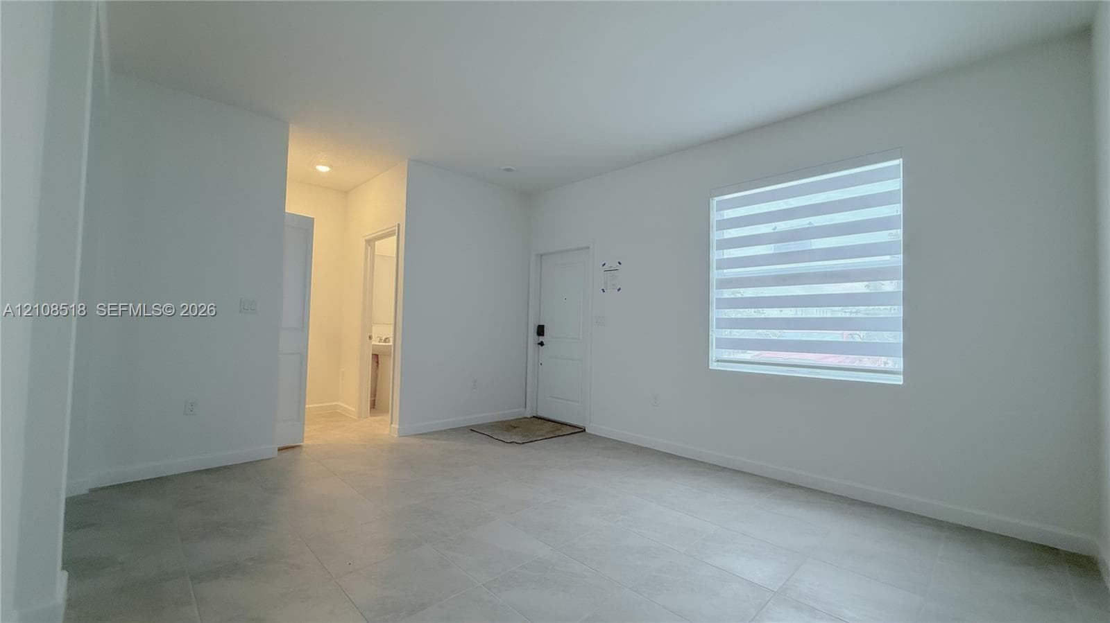 Interior space featuring neutral wall paint, large-format tile flooring, recessed ceiling lighting, and a single-panel entry door