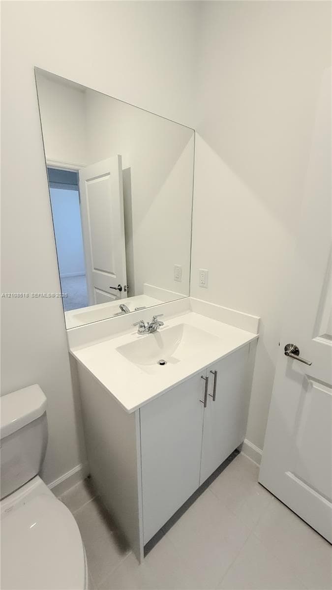White vanity cabinet with a solid surface countertop, integrated sink, chrome dual-handle faucet, and full-length vanity mirror