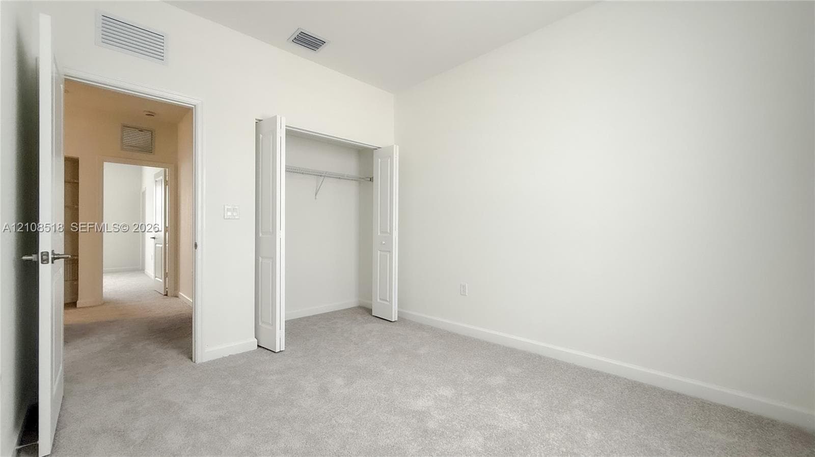 Neutral-toned wall paint, wall-to-wall carpeting, and a bi-fold door closet