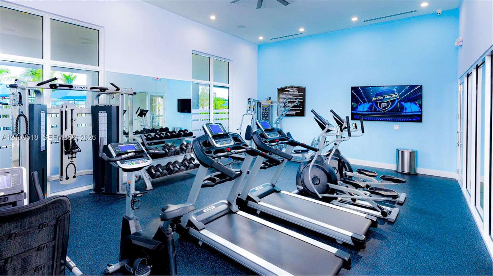 Fitness center featuring rubber flooring, floor-to-ceiling mirrored walls, recessed lighting, and expansive glass panels