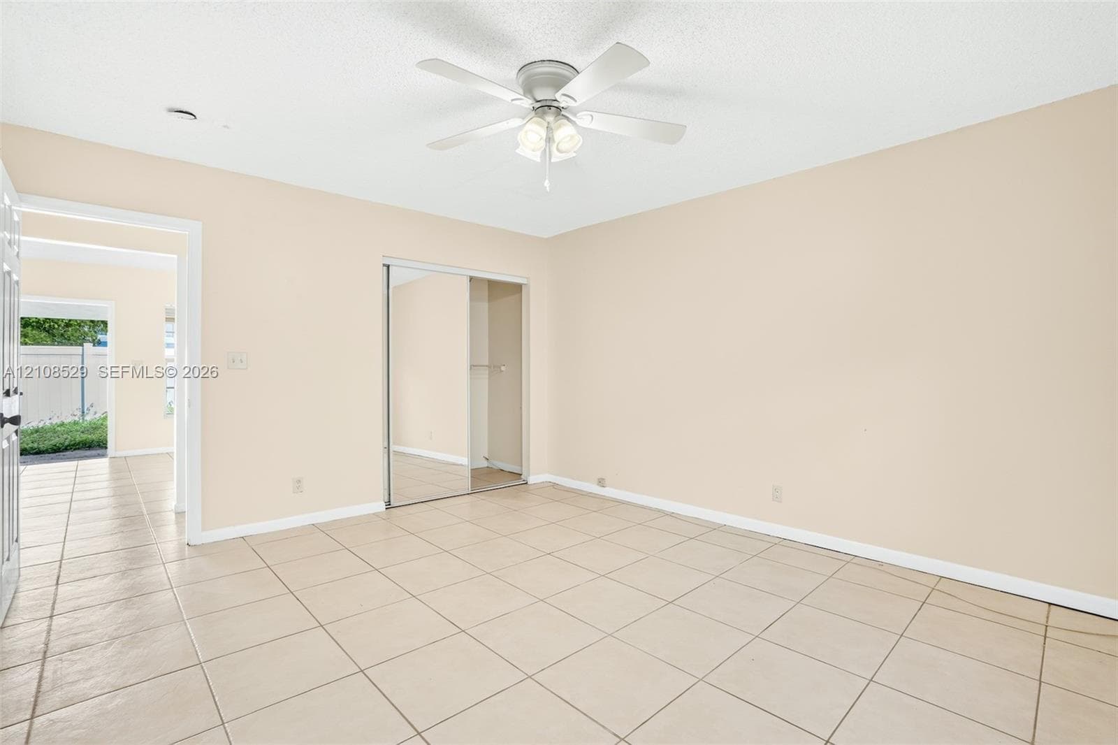 Neutral interior space featuring tile flooring, a ceiling fan with integrated lighting, and a closet with mirrored sliding doors