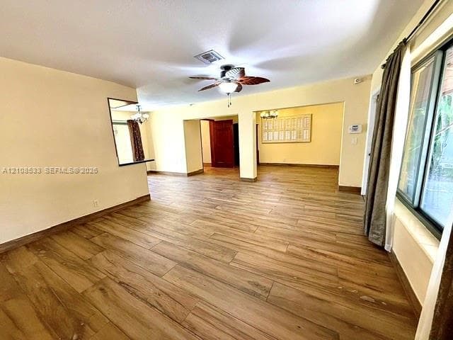 Open-concept interior featuring wood-finish flooring, a ceiling fan, sliding glass doors, and recessed pass-through window