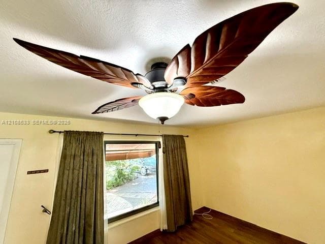 Ceiling fan featuring decorative leaf-shaped blades and a central dome light fixture, accompanied by wood-finish flooring