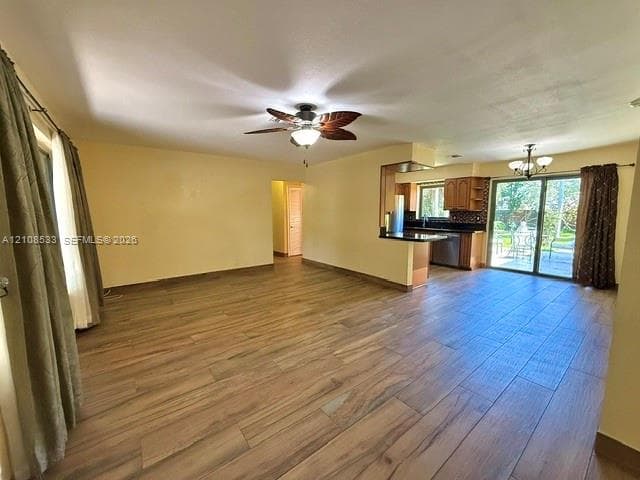 Open-concept interior featuring wood-finish tile flooring, a palm-leaf style ceiling fan, dark cabinetry, and sliding glass doors