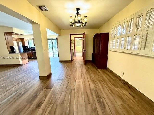 Interior space featuring wood-finish flooring, a multi-arm candelabra chandelier, and plantation shutters