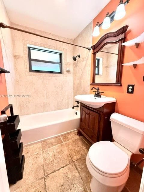 Bathroom featuring tile flooring, a tub-shower combination with tiled surround, a wood-finish vanity with a drop-in sink, an ornate wood-framed wall mirror, and three-bulb vanity lighting