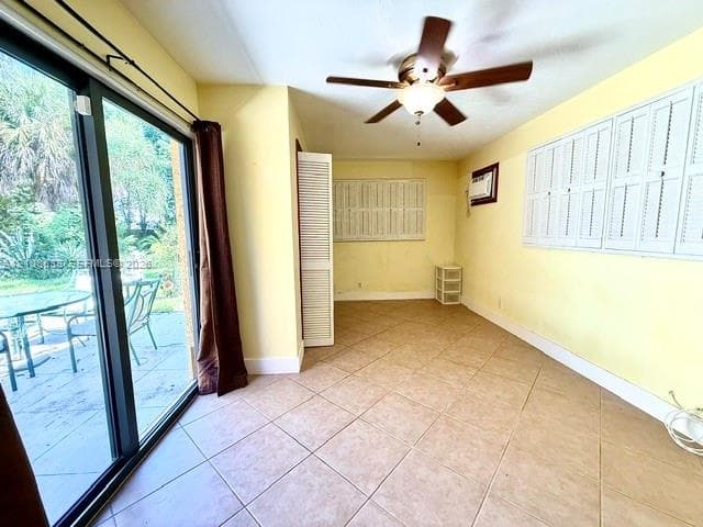 Sunroom featuring tile flooring, sliding glass doors, white louvered shutters, and a ceiling fan