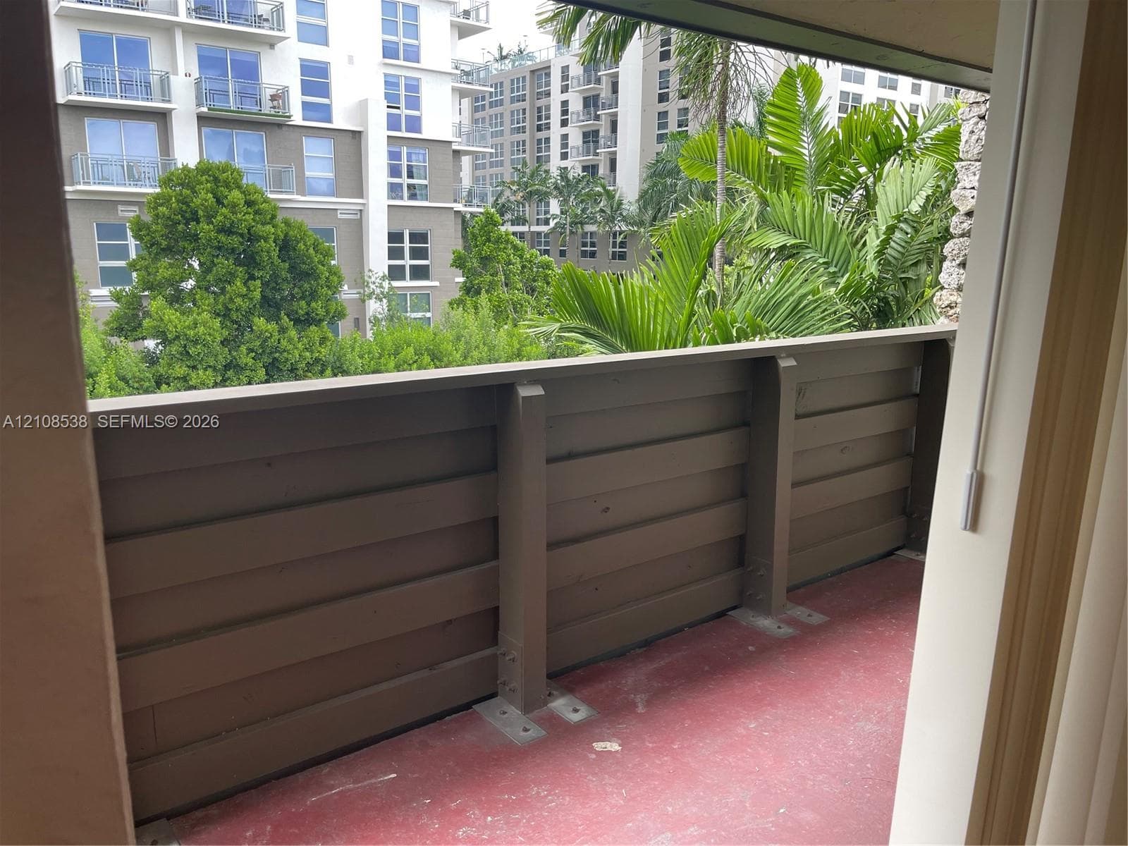 Private balcony featuring horizontal slat wood-finish railing and solid surface flooring