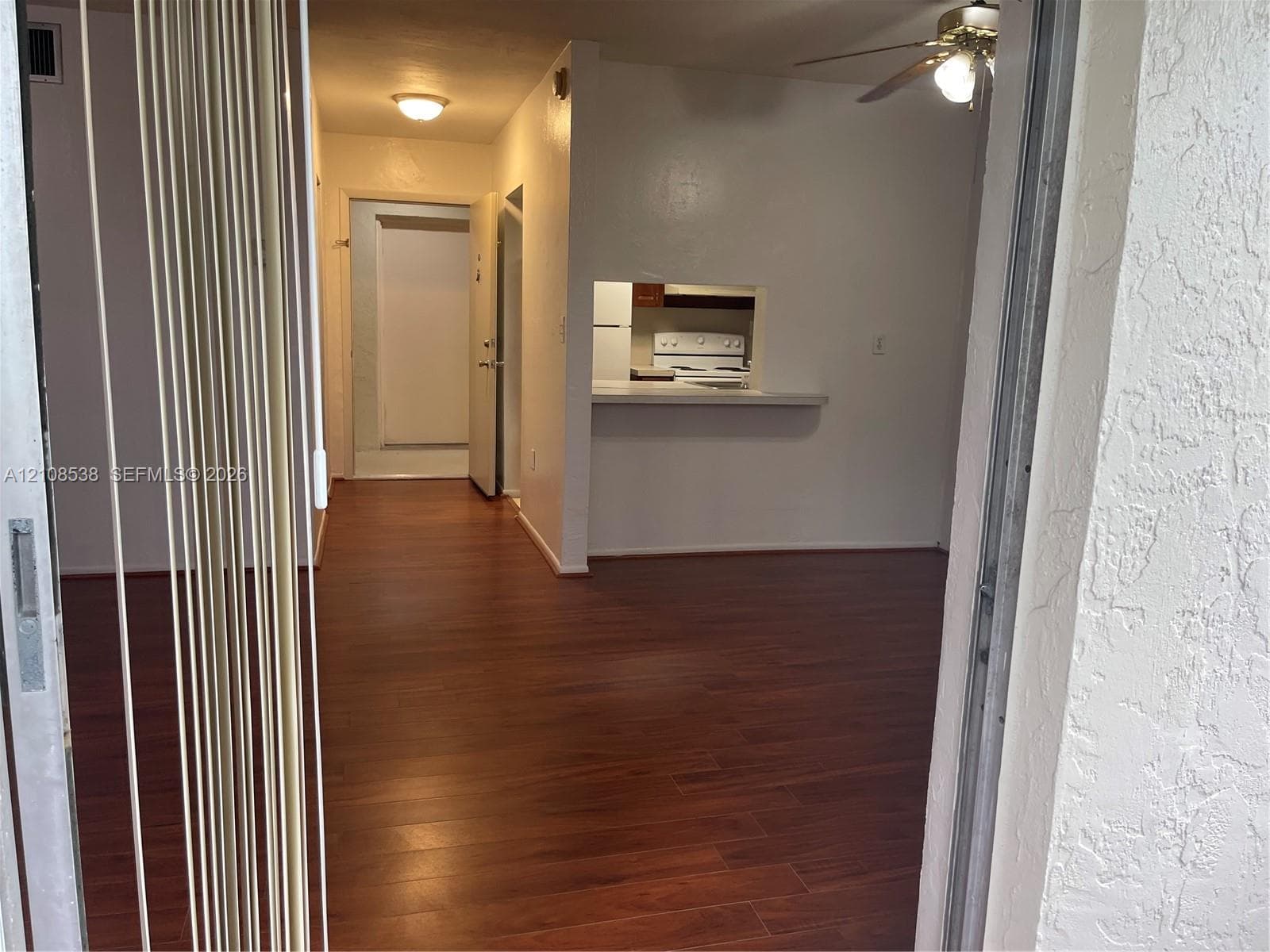 Interior featuring wood-finish flooring, a passthrough window to the kitchen, a ceiling fan, and recessed lighting