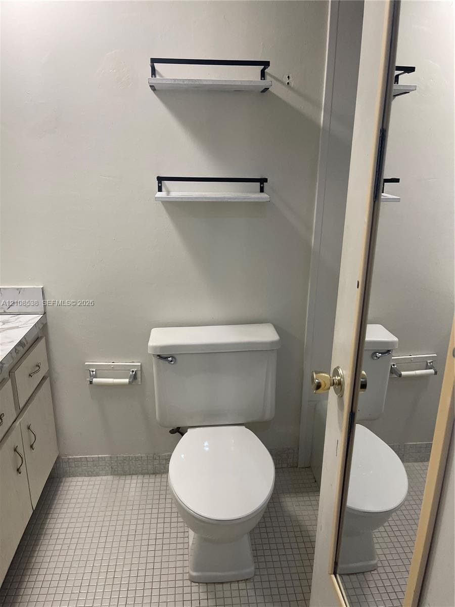 Vanity with a solid-surface countertop, dual wall-mounted floating shelves with metal accents, and mosaic tile flooring