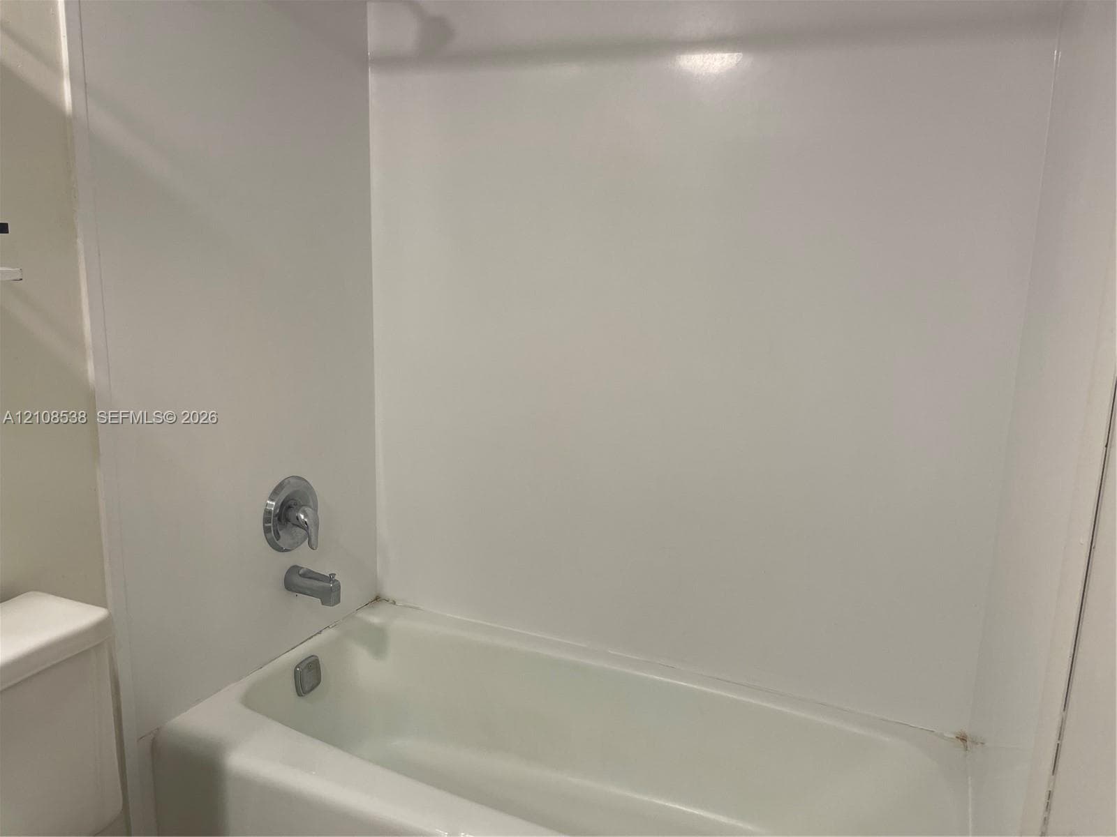 Bathtub and shower combination featuring a polished chrome single-handle mixing valve and matching tub spout